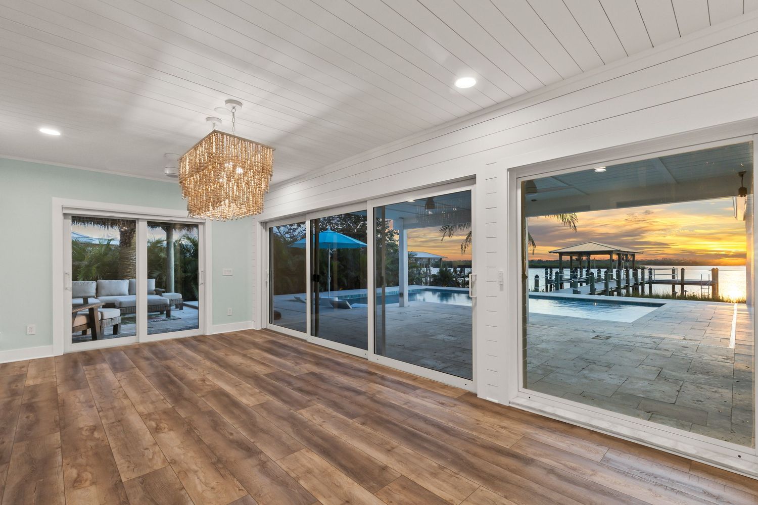 Modern coastal home interior features white plank ceilings, panoramic ocean views, and warm wood flooring throughout.
