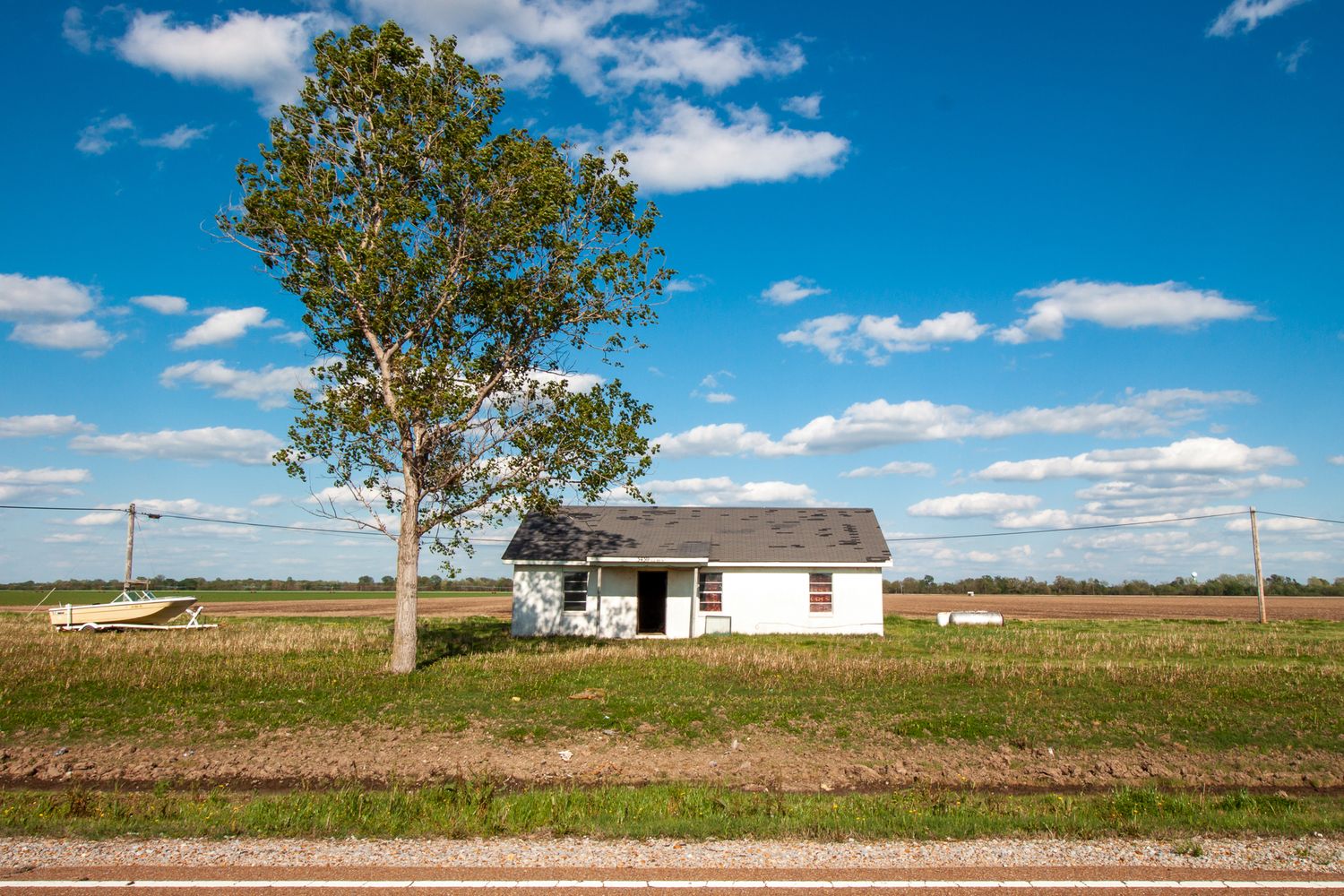A small house sits next to a tree and boat in Mississippi