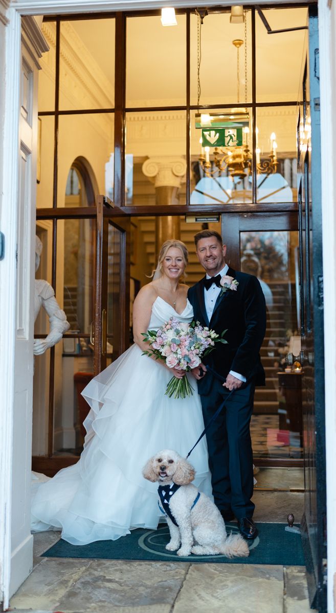 Bride and groom with their cute cockapoo do at entrance of Bowcliffe Hall - editorial and candid wedding photographer Yorkshire