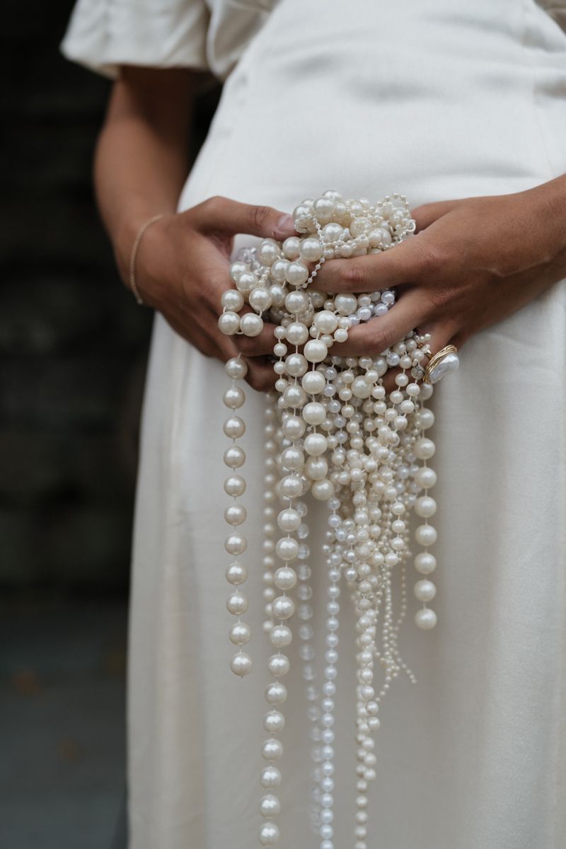 Bride clutching her pearl accessories on her wedding day in Castlefield room in Manchester - editorial wedding photographer in Manchester