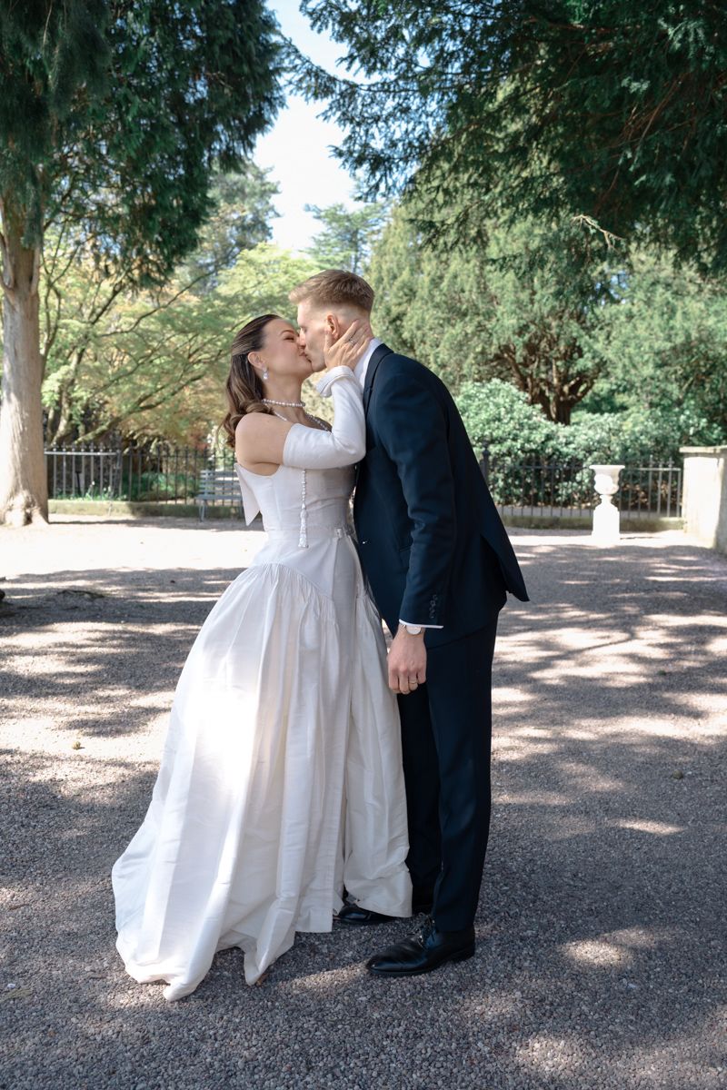 Bride and groom kissing on the grounds of Capesthorne Hall - editorial bridgerton style wedding photography Cheshire