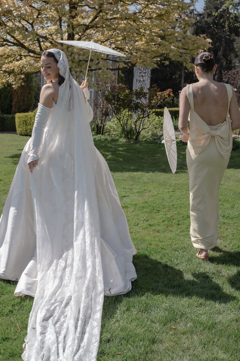 Bride walking the grounds of Capesthorne Hall with sun parasol and long veil - editorial wedding photographer Cheshire