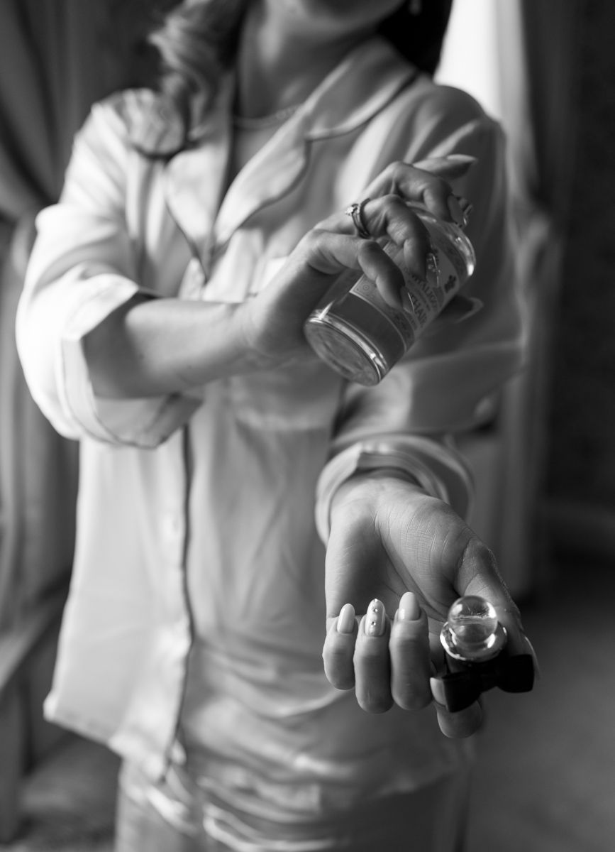 Bride spraying perfume on her wedding day, portrait by the window at Eaves Hall, Lancashire  - editorial wedding photographer  in Lancashire