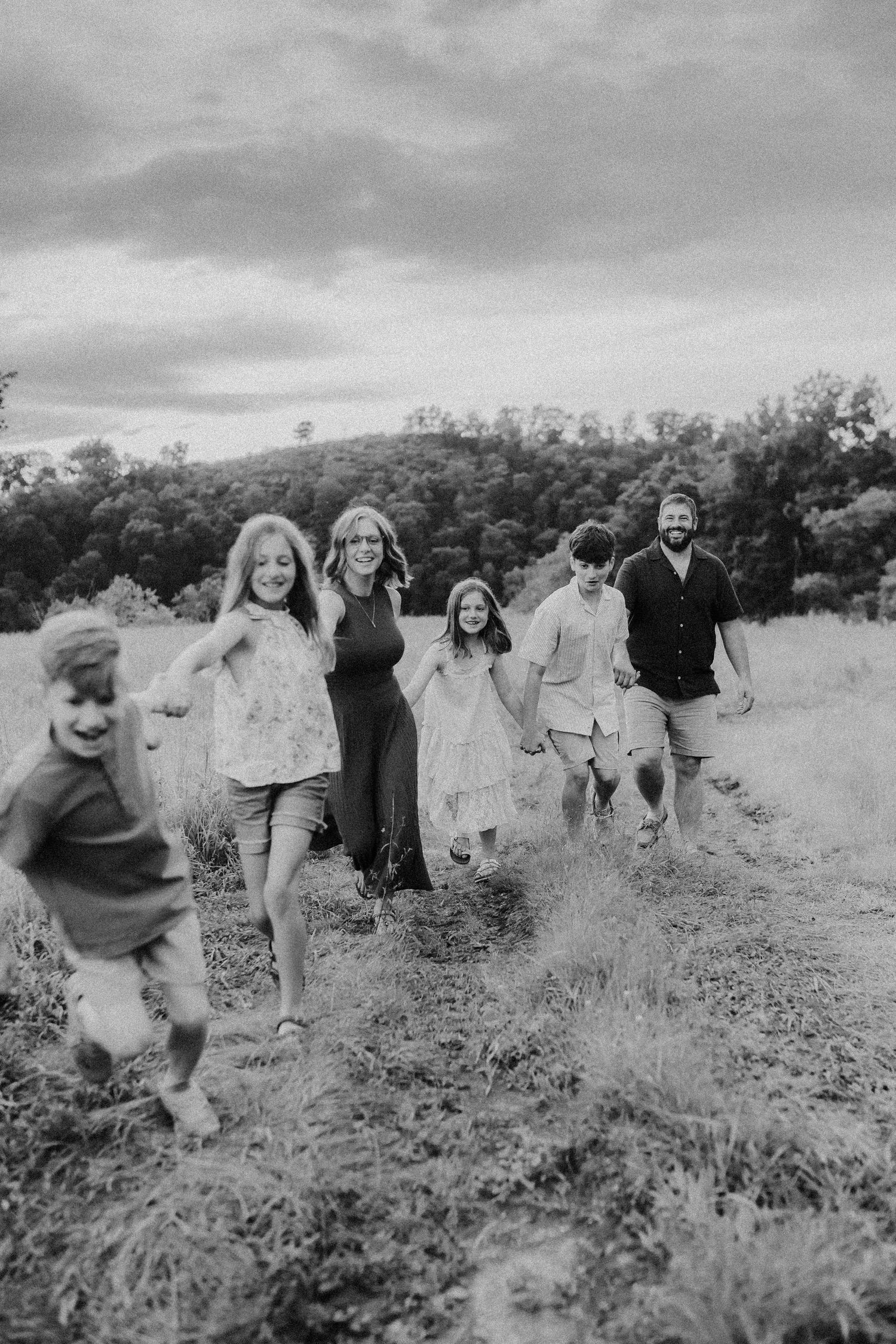 [Historical black and white photo sequence shows group of people playfully tumbling and rolling down a grassy hillside.
