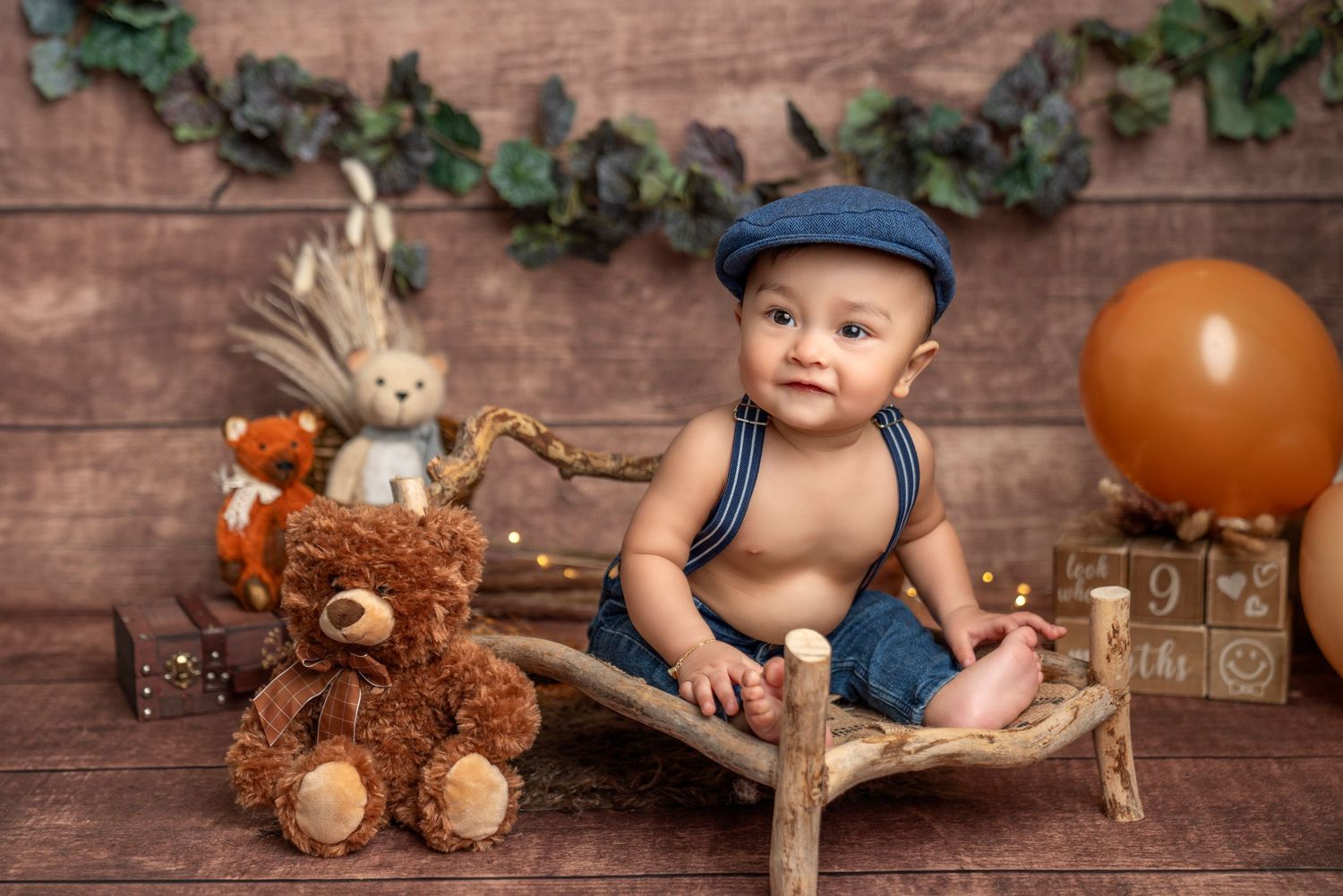 Baby in blue overalls sitting on wooden prop, Lina Alvarez Photography, newborn baby photography