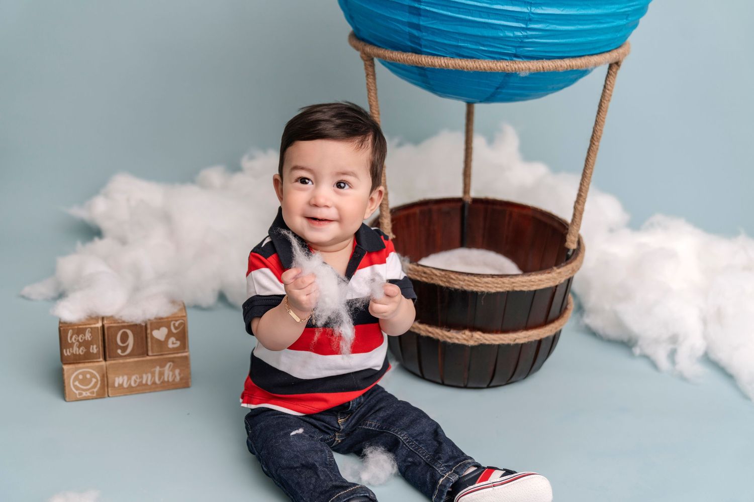 A whimsical hot air balloon themed photo setup with cotton cloud decorations.