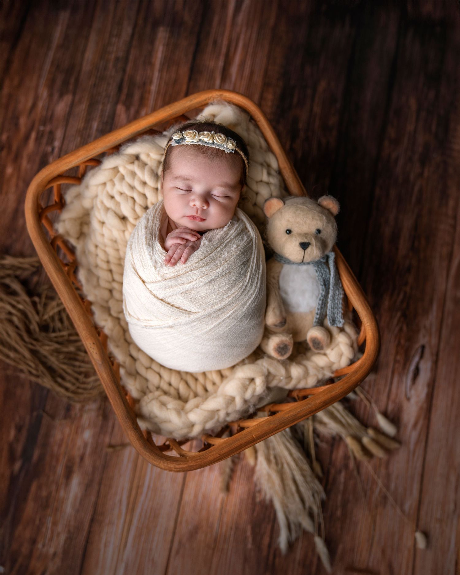Newborn wrapped in cream blanket with teddy bear companion in rustic wooden basket. newborn , maternity and family photographer near me