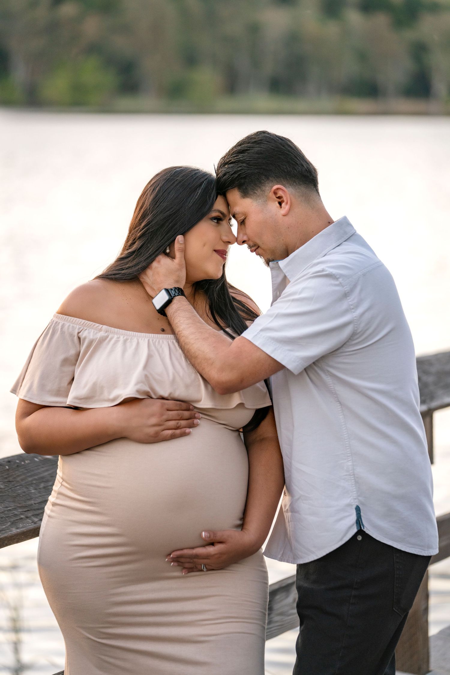 Intimate maternity photo at sunset with couple in neutral tones.