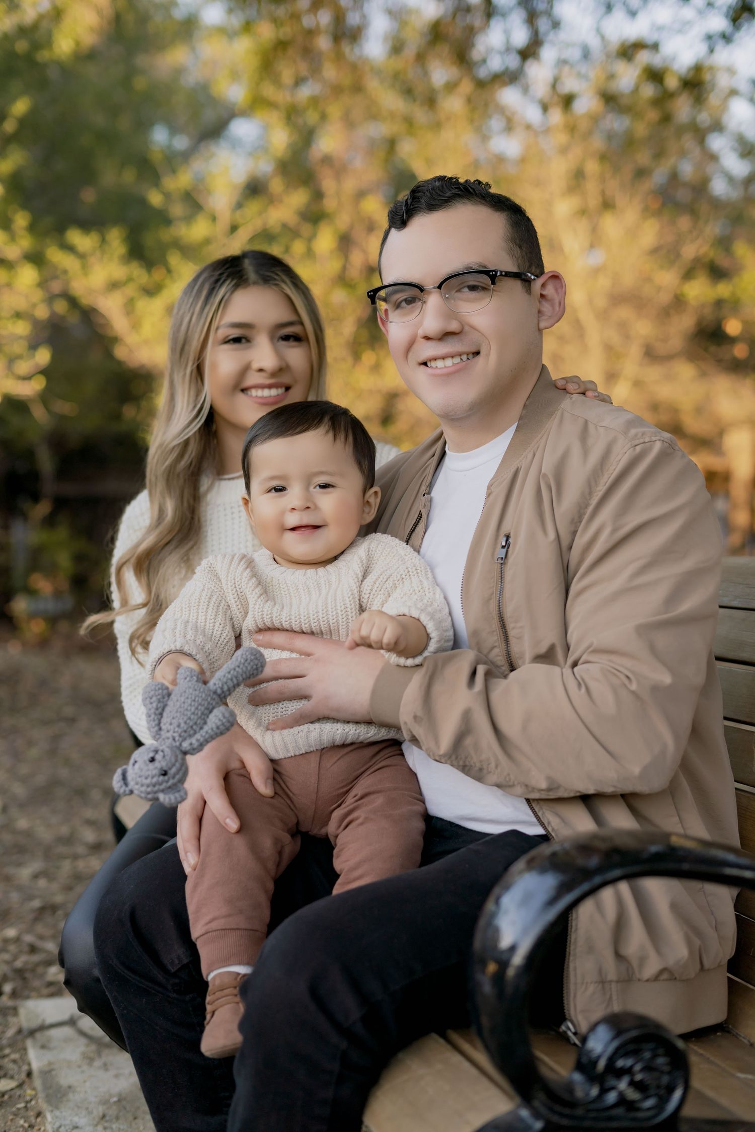 Family sits together on bench outdoors, family portrait photography, family photography near me, lina alvarez photography