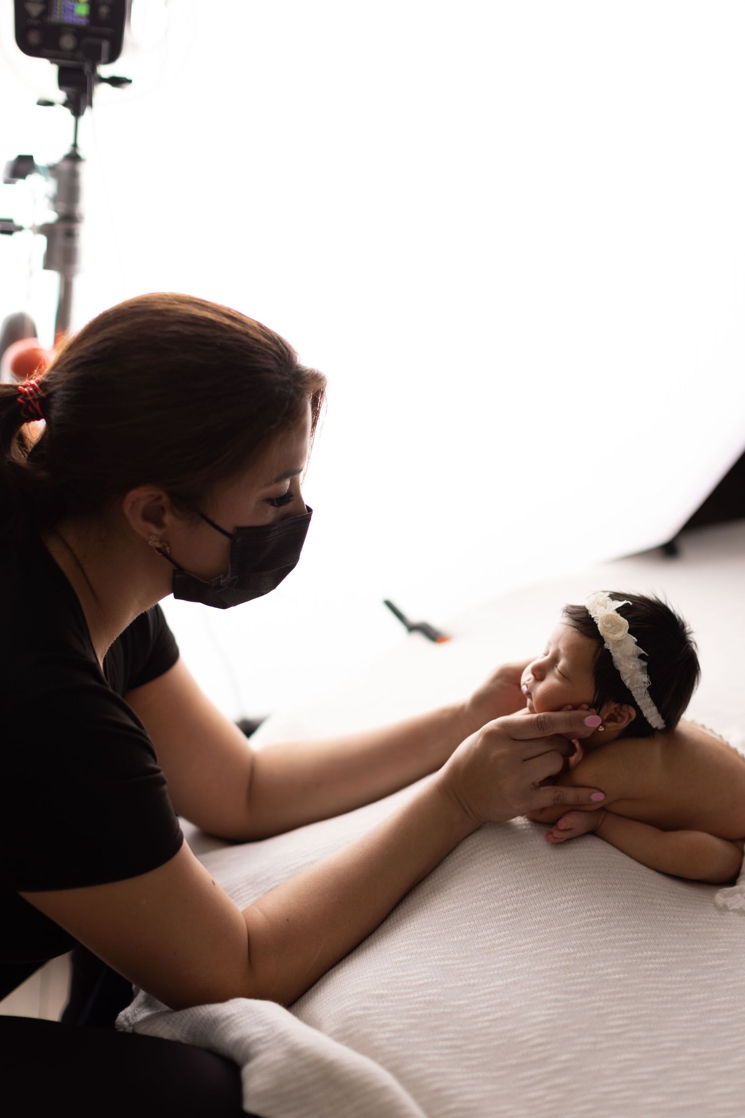 Photographer wearing black mask carefully positions subject during professional photoshoot.