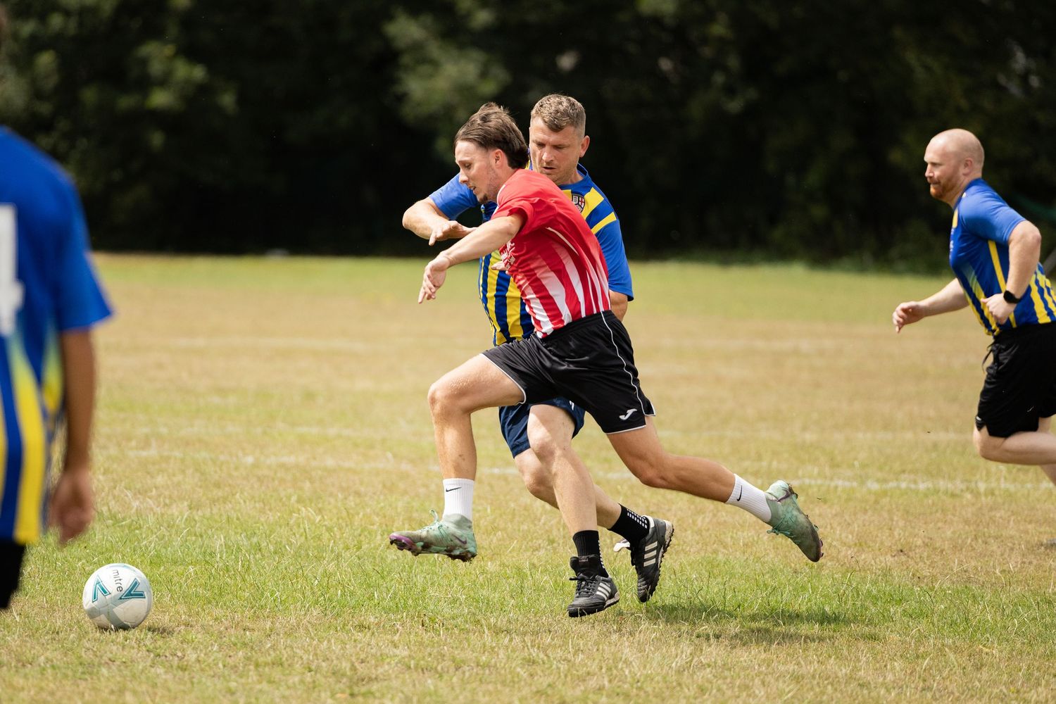 Soccer players competing for ball possession during a match on a grass field.