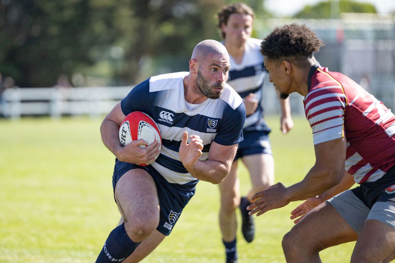 Two rugby teams compete intensely for ball possession on a green sports field.