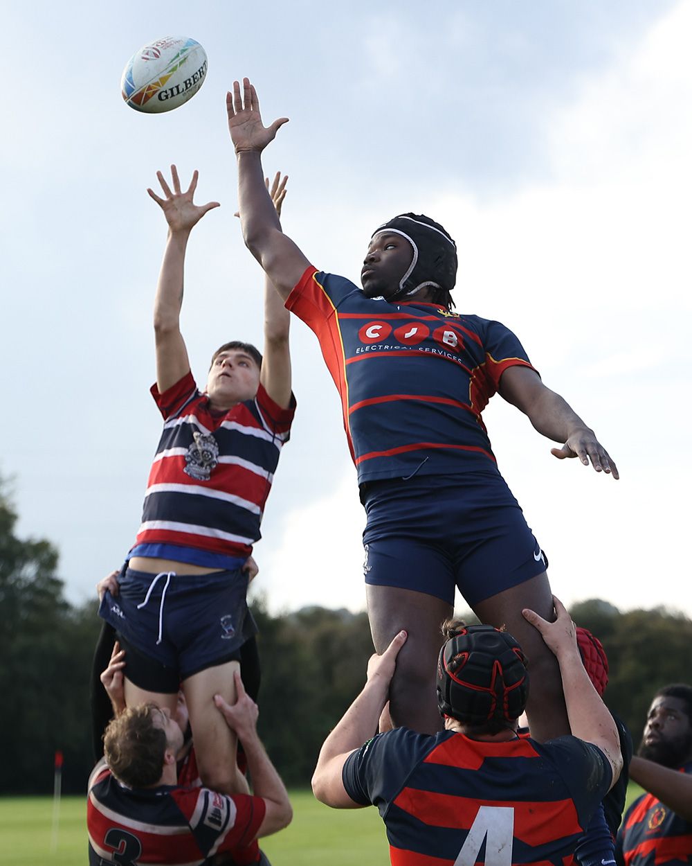 Rugby players leap high into the air during a lineout play to compete for possession of the ball.