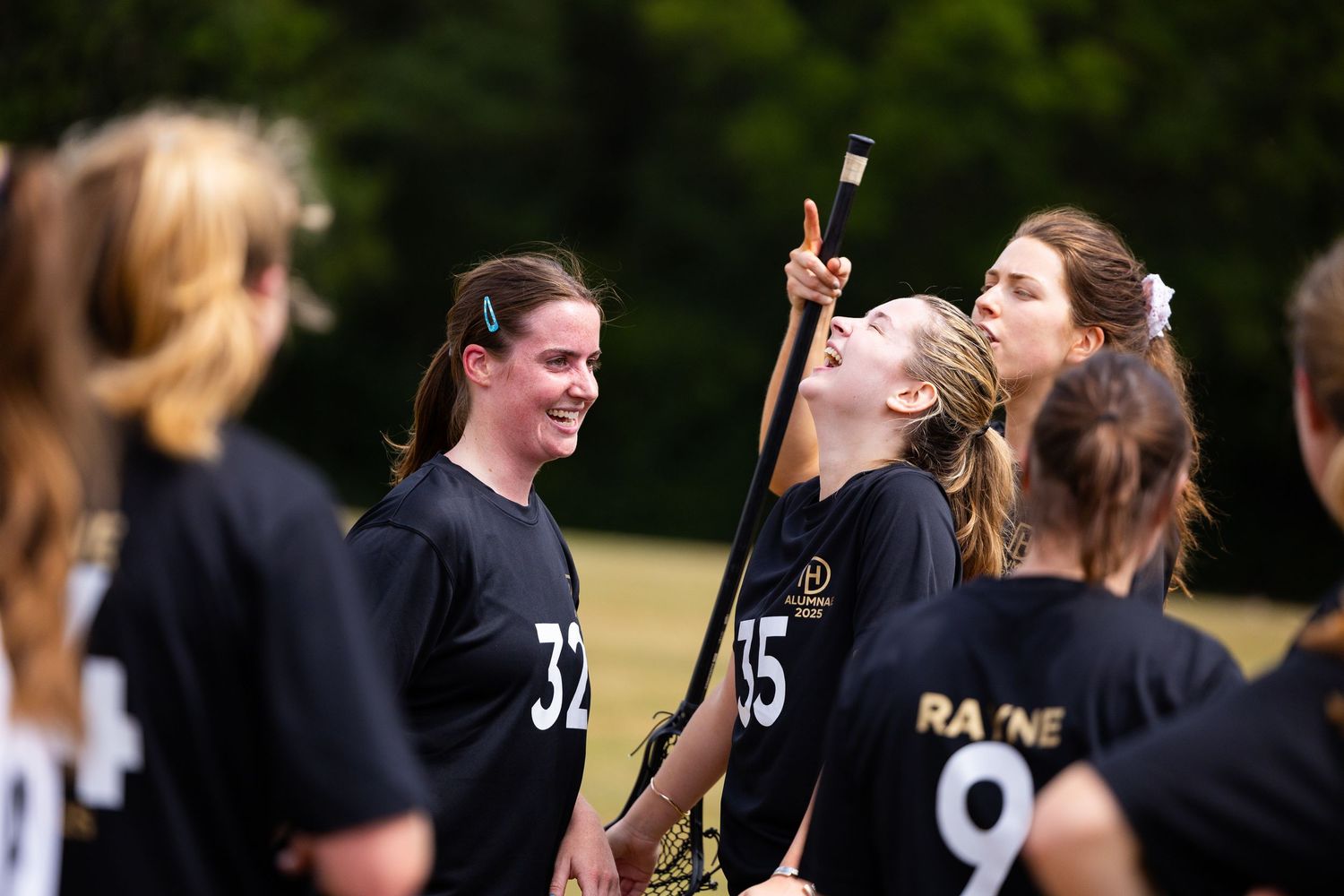 Athletes in black uniforms celebrating during outdoor sports match.
