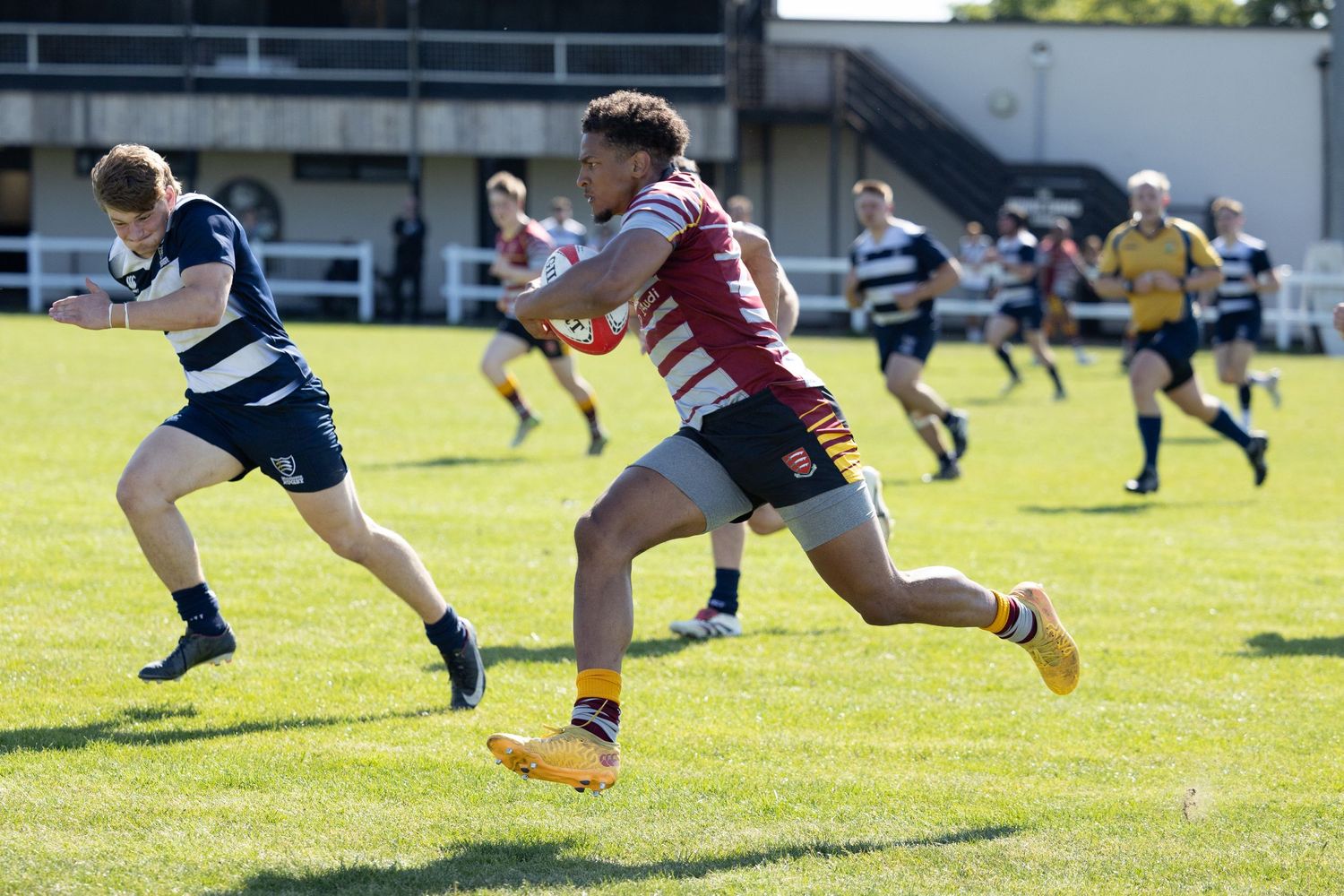 Multiple rugby players running and leaping during a match on a grass field.