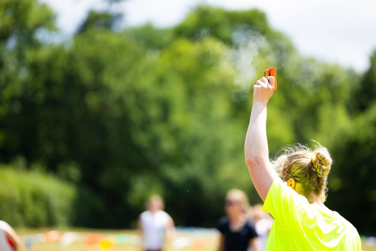 Group of runners in bright yellow shirts start their race on a sunny summer day at a local fundraising event.