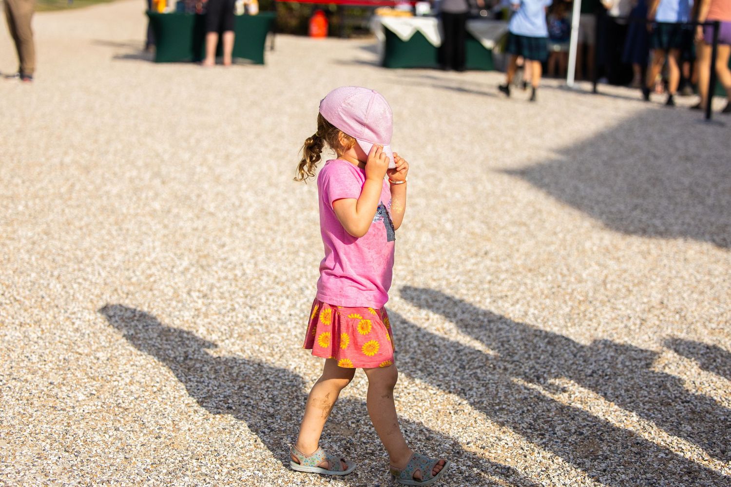 Young child in pink outfit playing outdoors on sunny day.