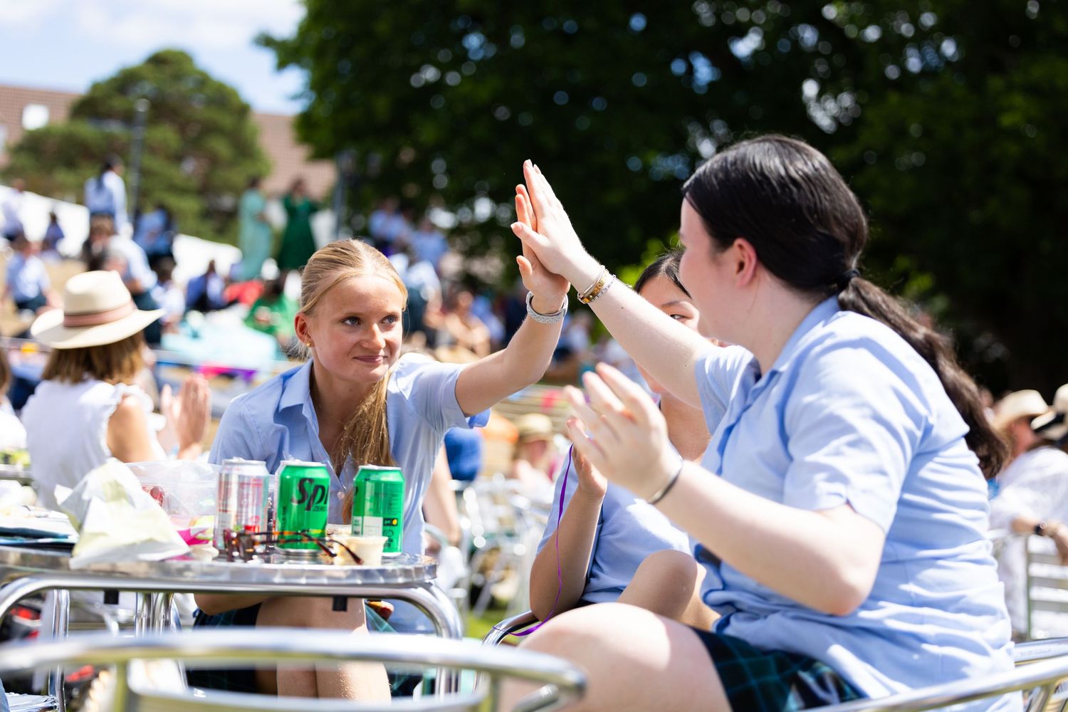 People enjoying drinks and conversation at an outdoor summer event with table service.
