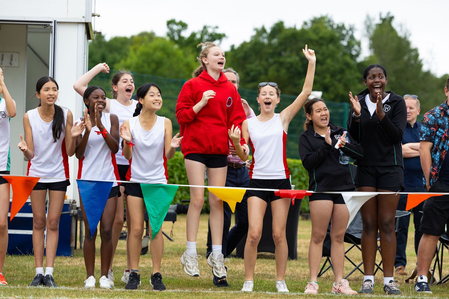 Athletic group celebrates and jumps with excitement together during an outdoor sports event.