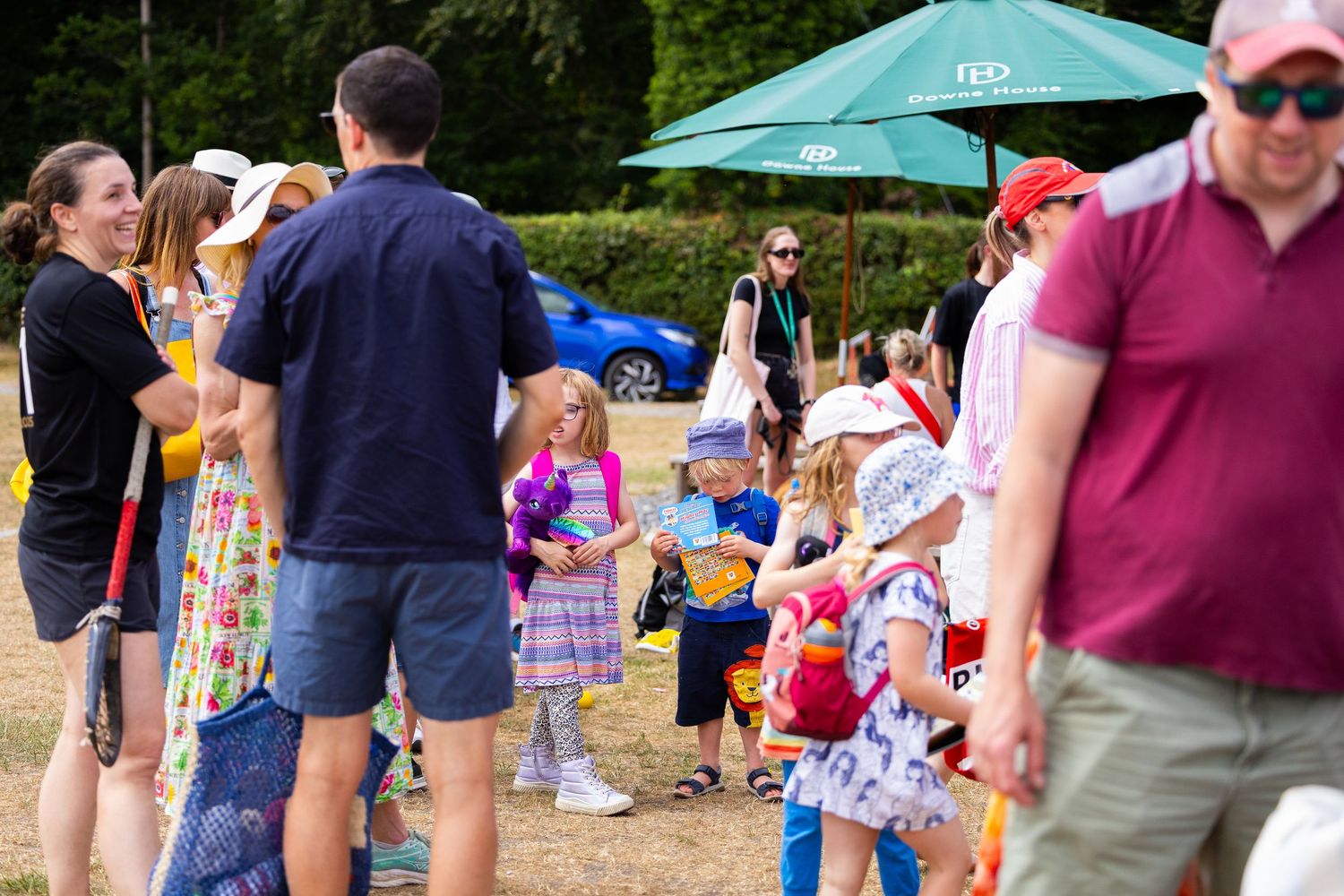 Crowd of people enjoying an outdoor summer festival with umbrellas and tents.