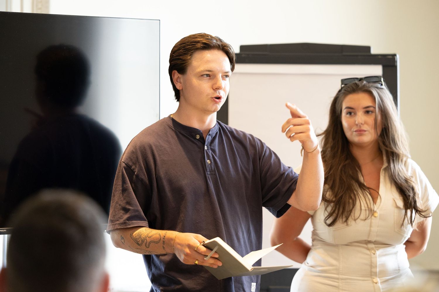 Two individuals giving a business presentation in a bright office meeting room.