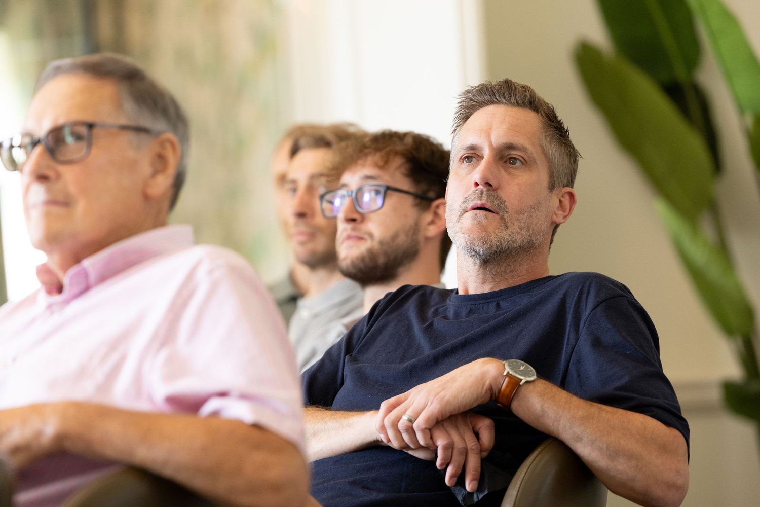Group of people engaged in a focused business discussion around a modern office table.