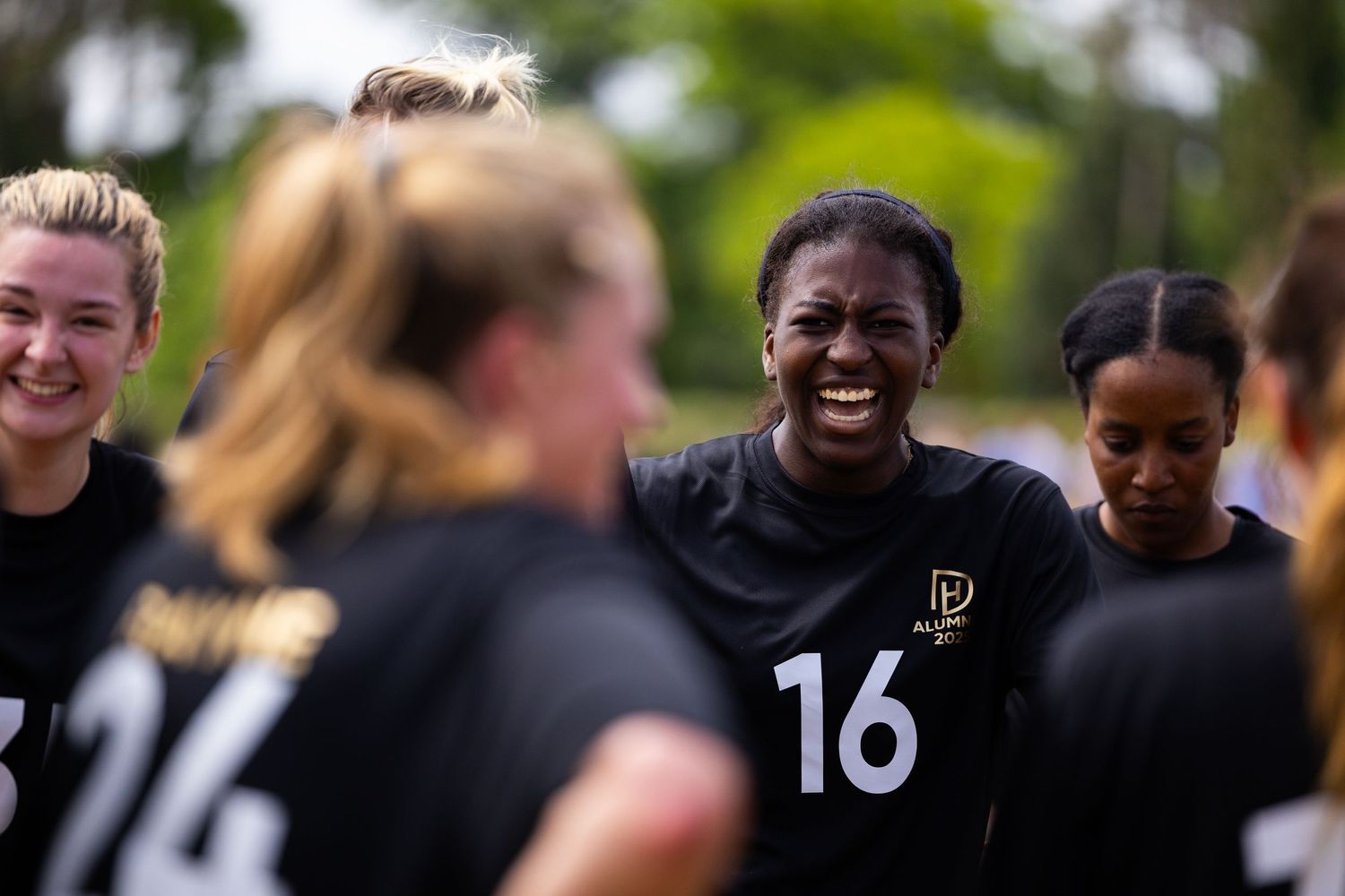 Team members in black jerseys sharing joyful moment during game.