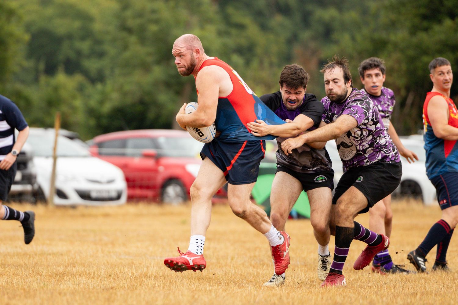 Athletes competing in a rugby scrum formation on a sunny field.