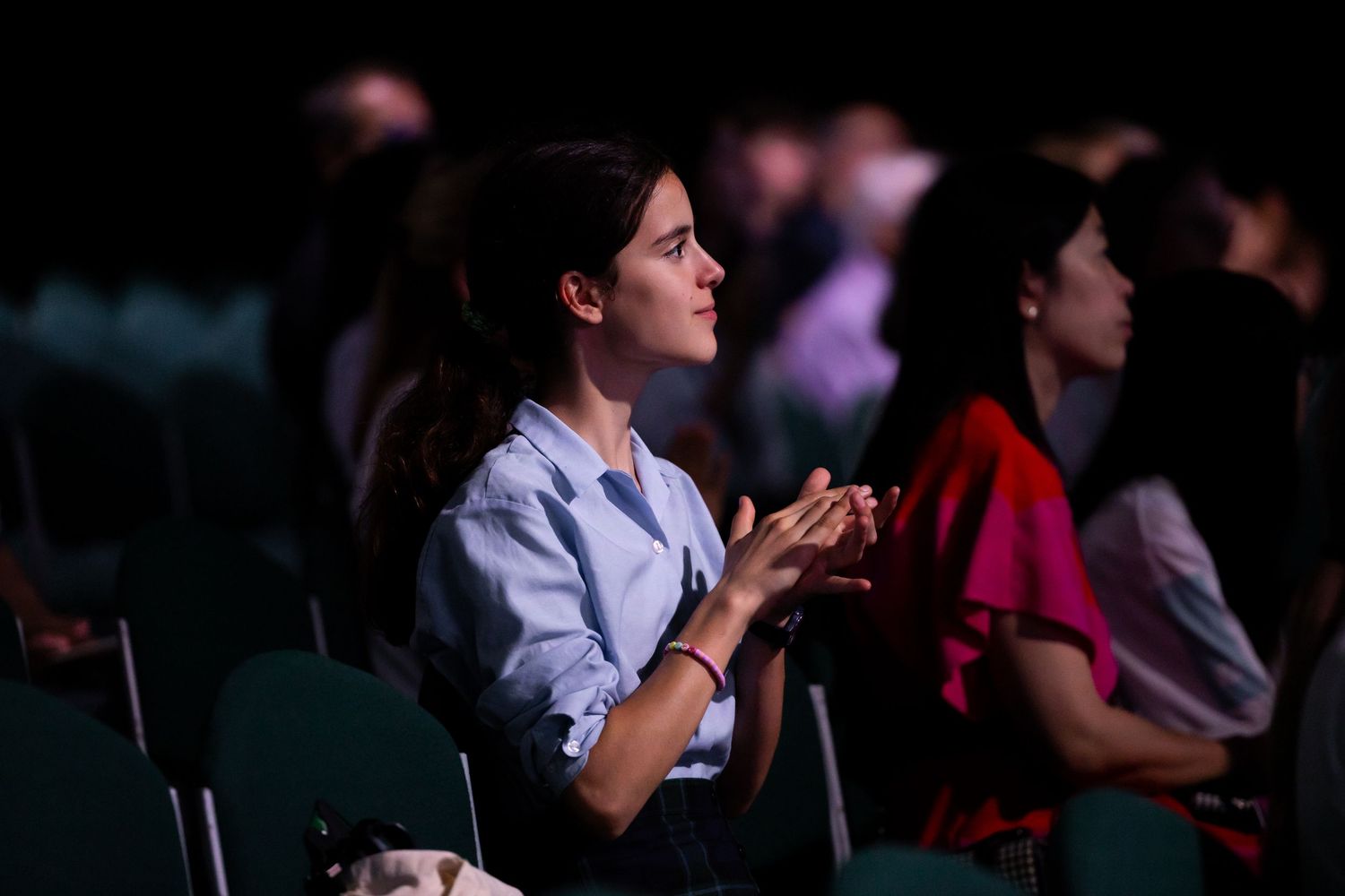 Person applauding during a dimly lit indoor event or performance.