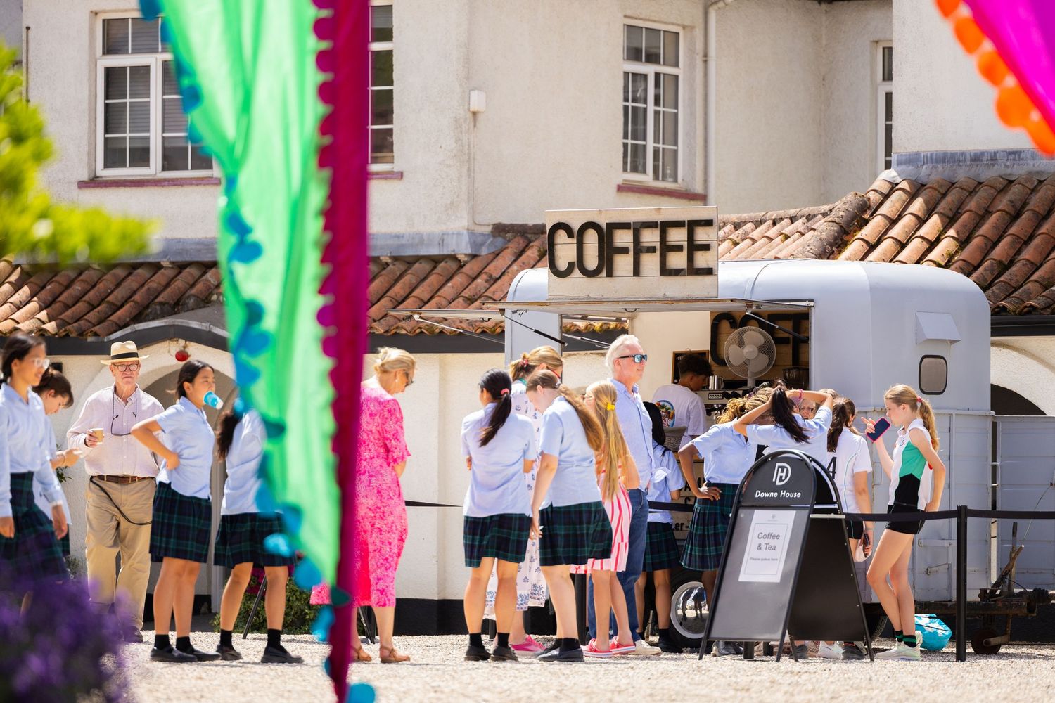 Students gathering near a coffee stand with colorful decorative banners at a school event.