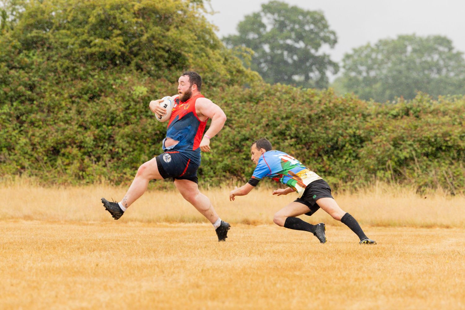 Rugby players sprint across a sun-baked field during an intense match sequence.