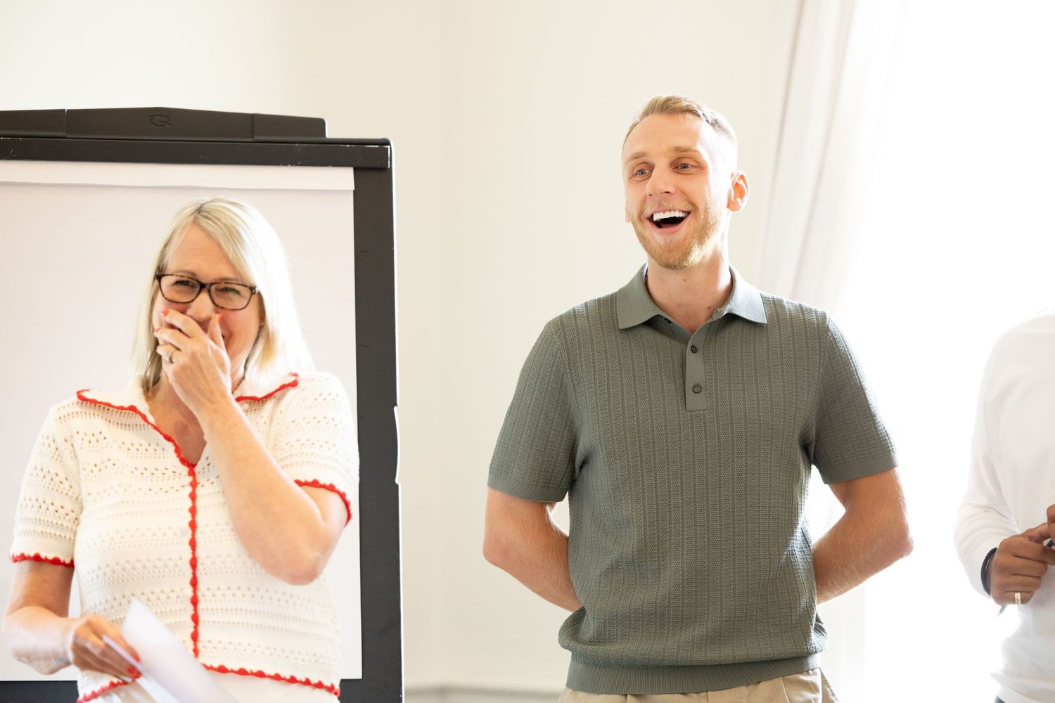 People sharing a lighthearted moment during a business meeting near a whiteboard.