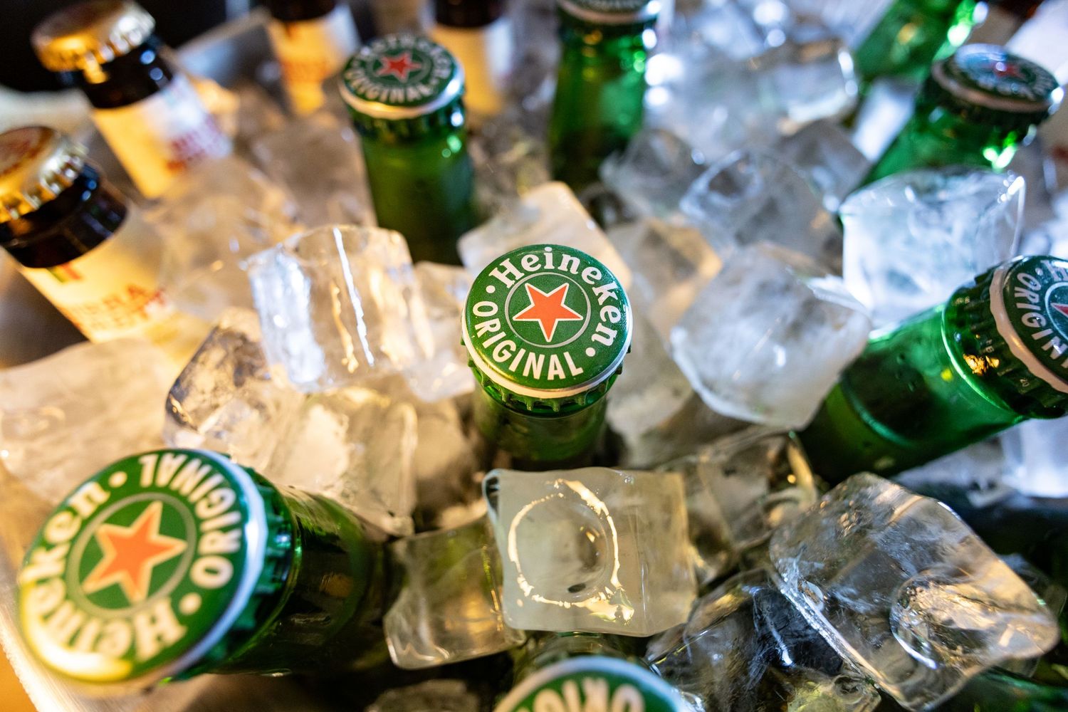 Heineken beer bottles chilling in ice during a celebration or party.