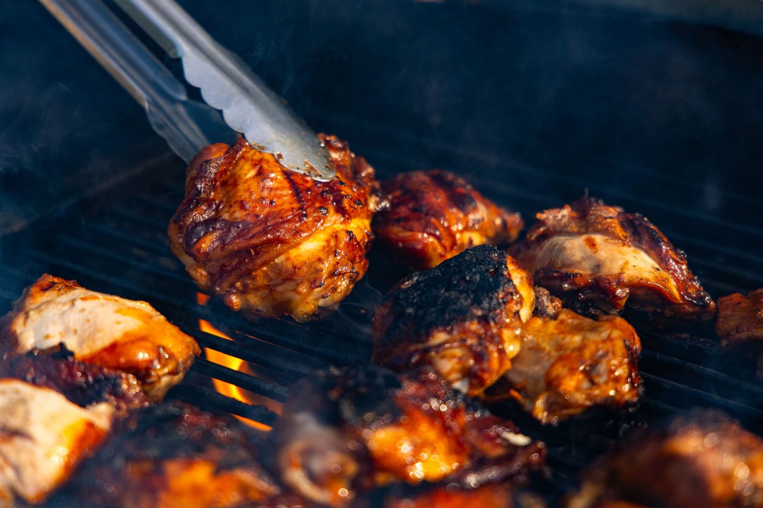 Juicy grilled chicken pieces with caramelized glaze cooking on a barbecue grill.