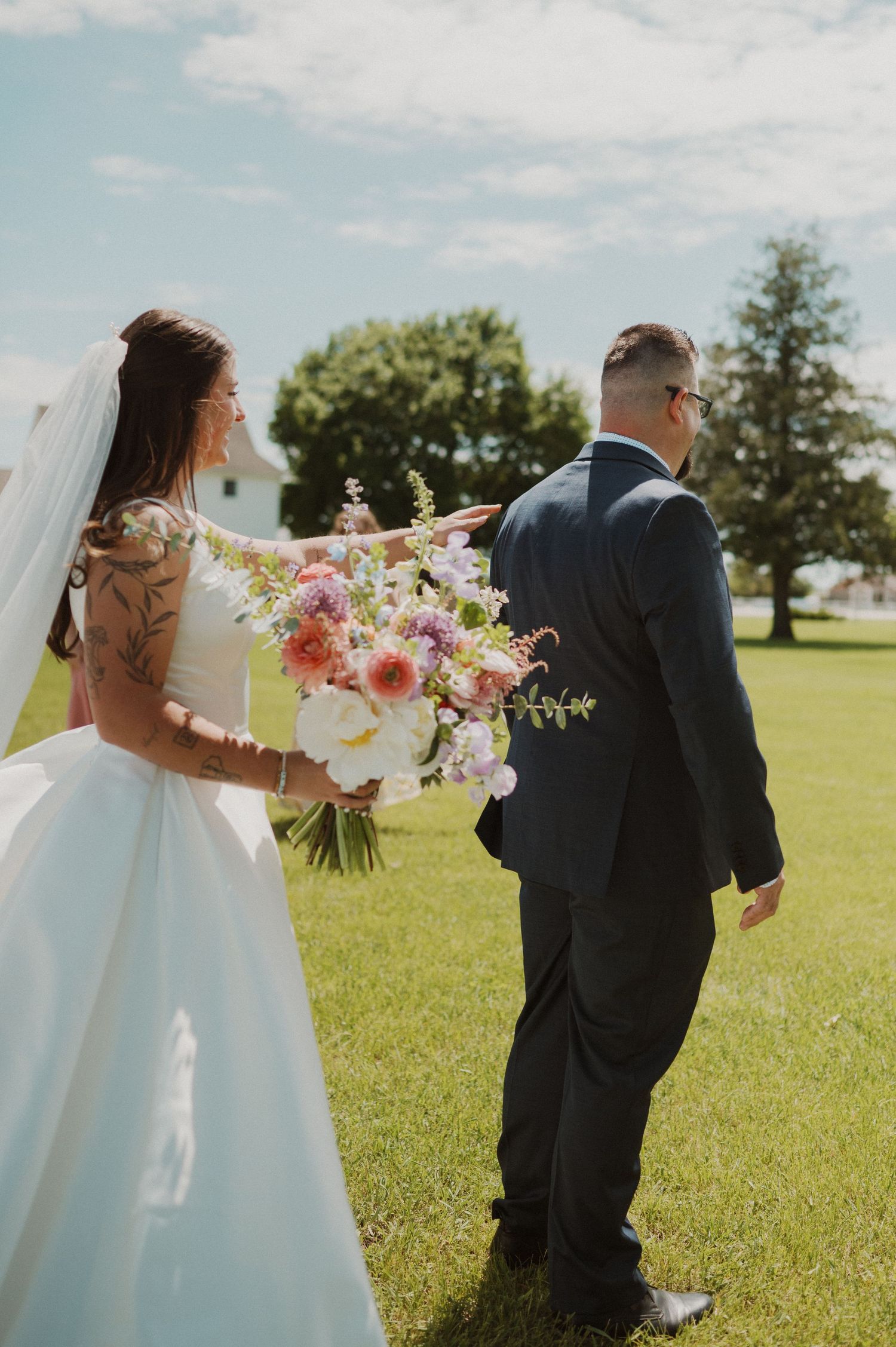 A bride holding a colorful floral bouquet walks with her groom on their wedding day.