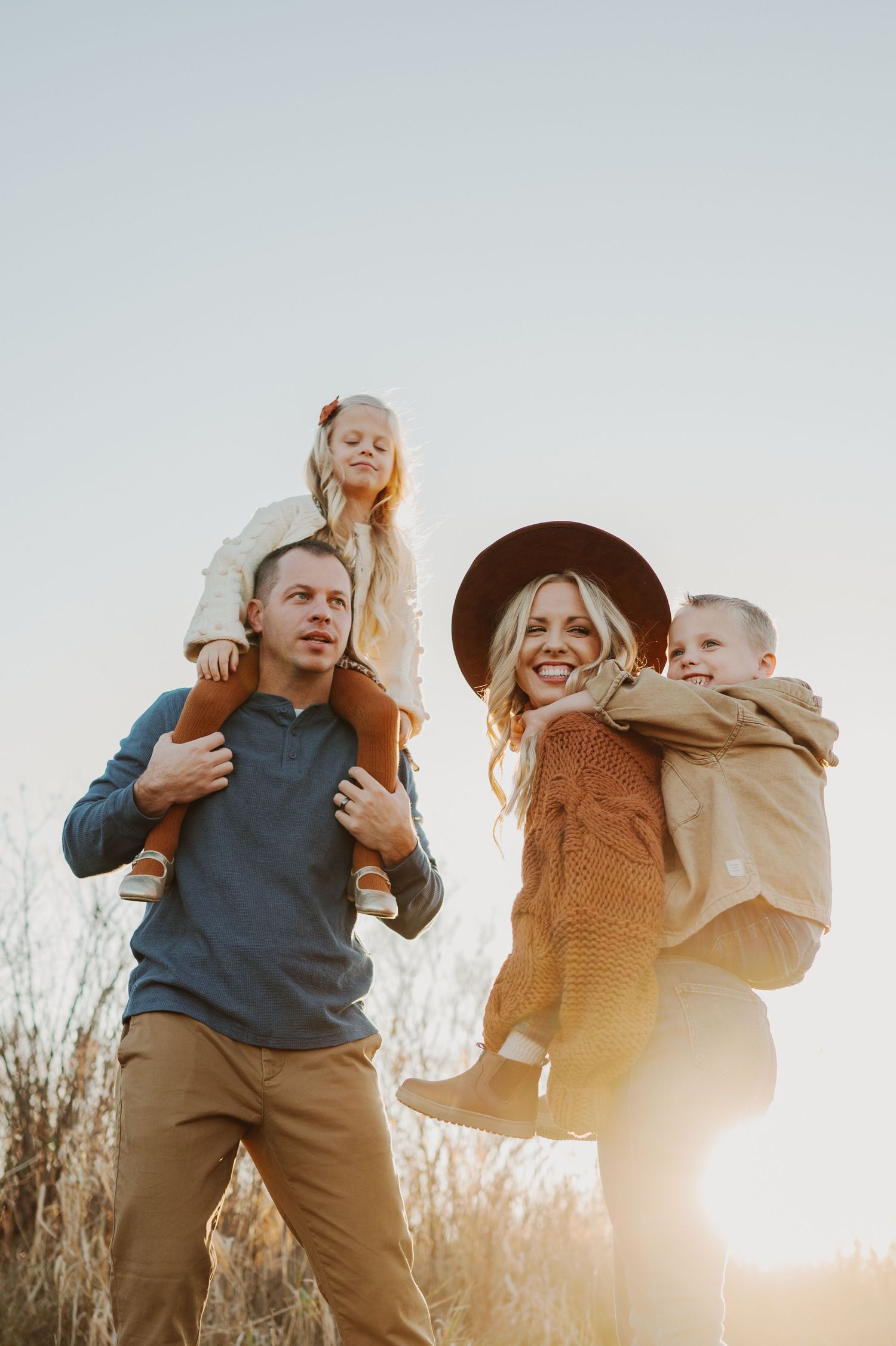 A family enjoys a sunset moment together in tall grass during golden hour.