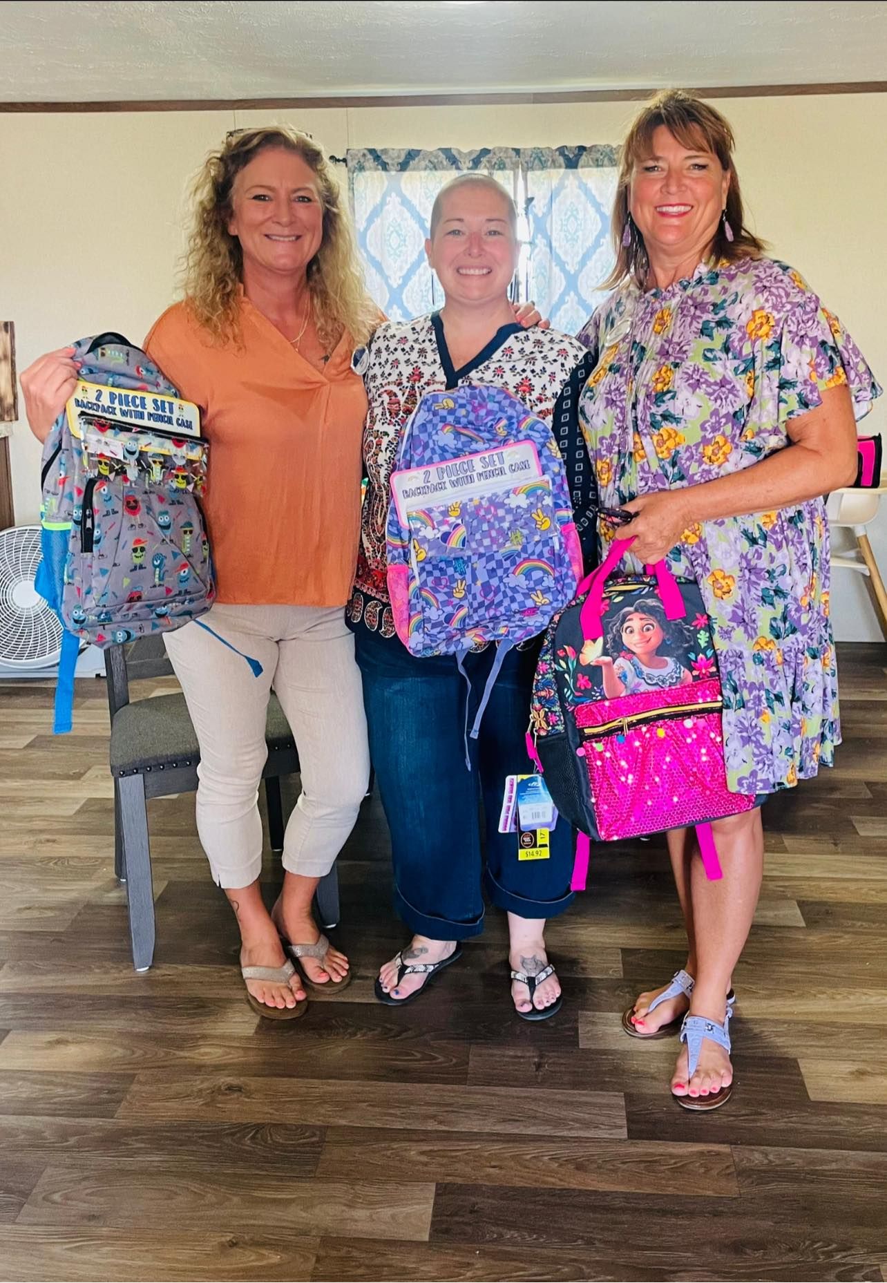 A group shows off colorful floral print scrubs and bags while posing together.