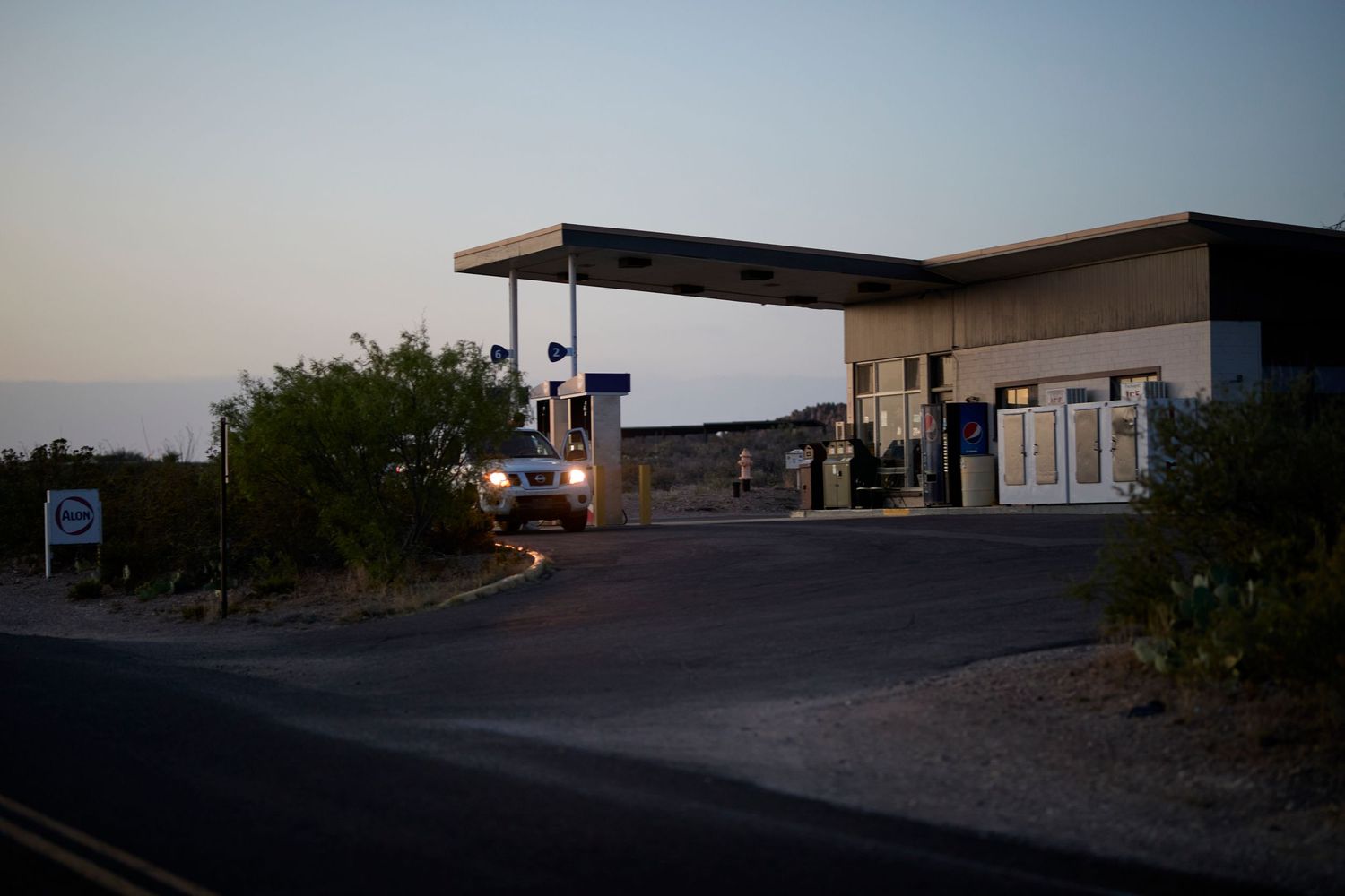 Modern gas station with flat roof architecture at twilight in desert setting.