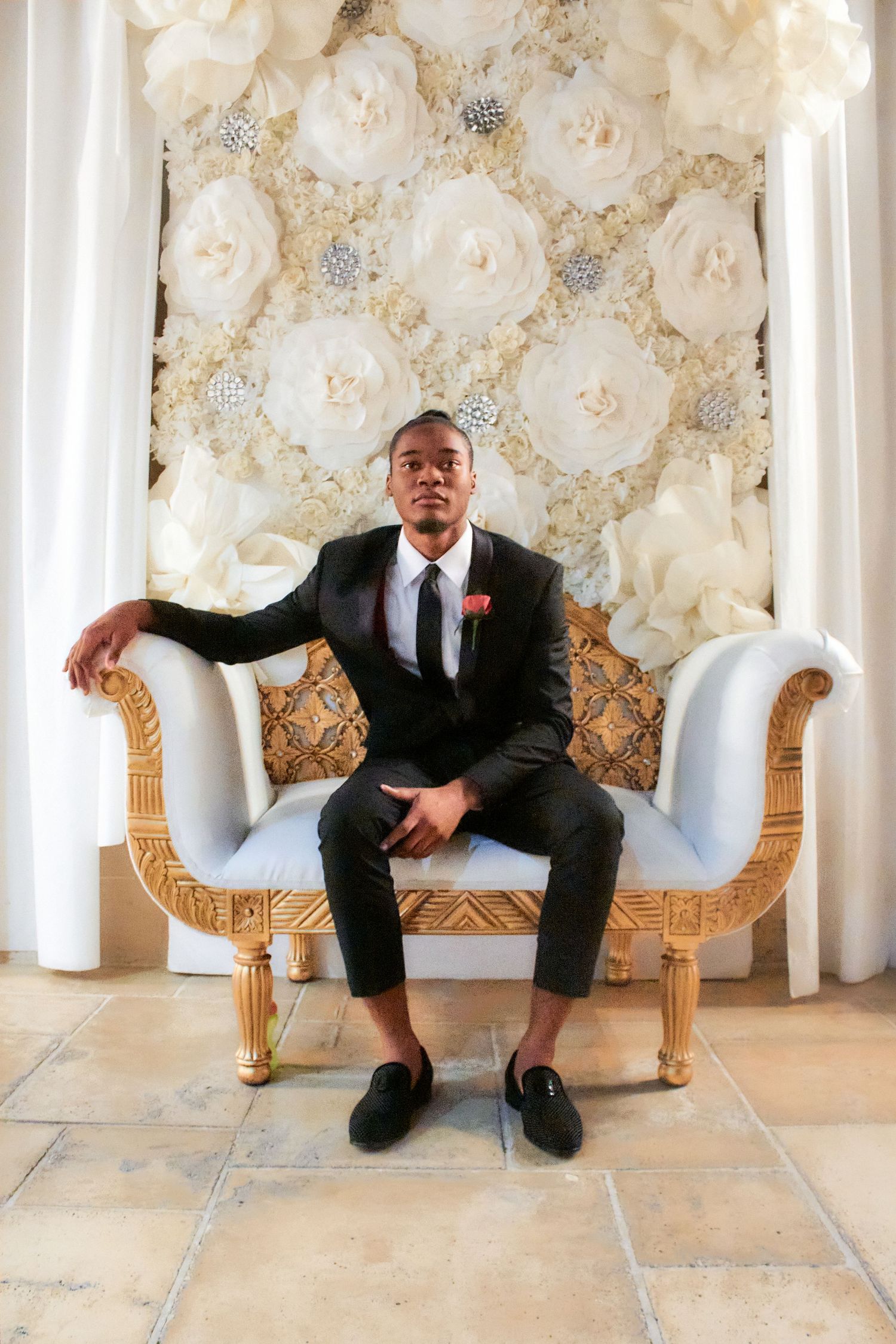 Formal portrait on an ornate white settee against a floral backdrop.