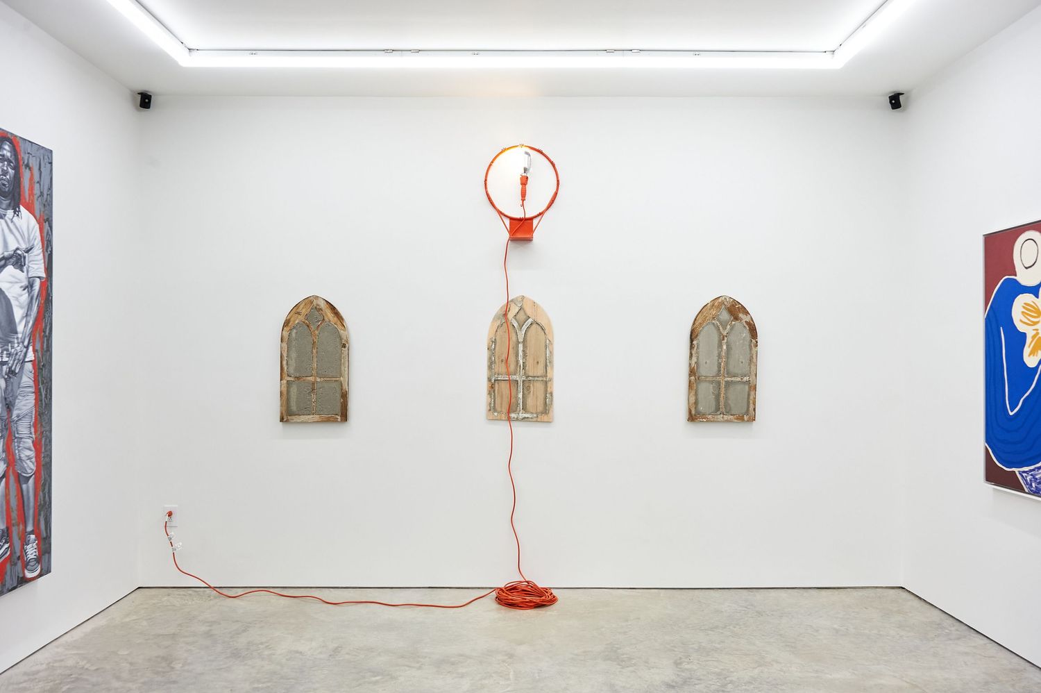 White gallery space with three framed artworks and a red balloon installation on the wall.