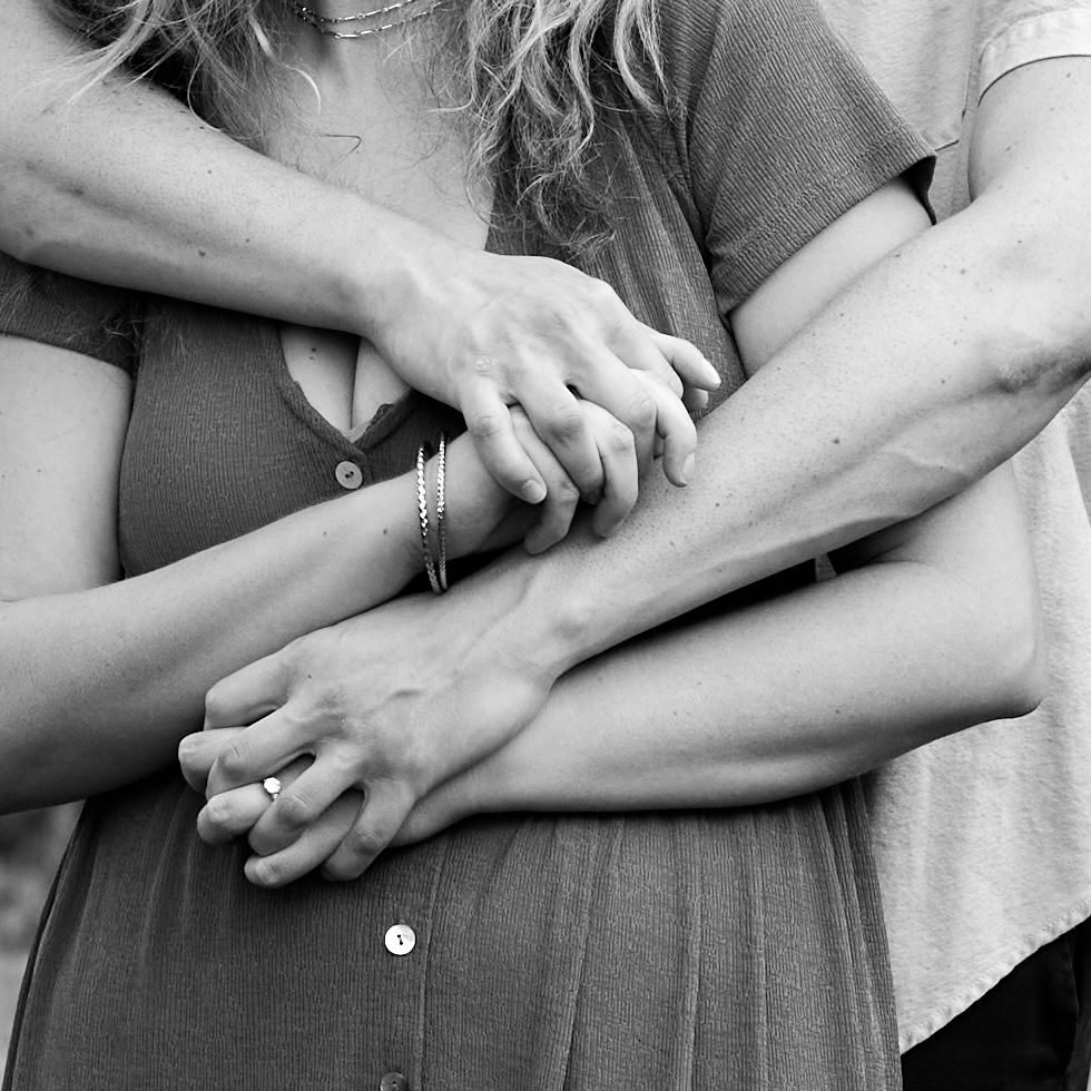 Close-up black and white image of hands holding each other intimately.