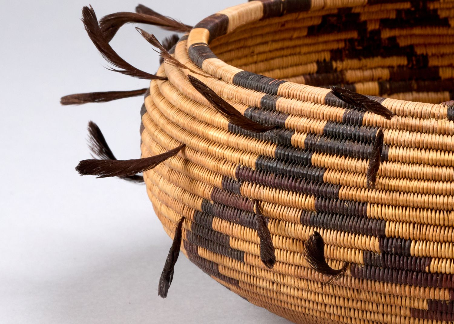 Detailed view of Native American basket weaving with dark geometric designs on natural fiber.