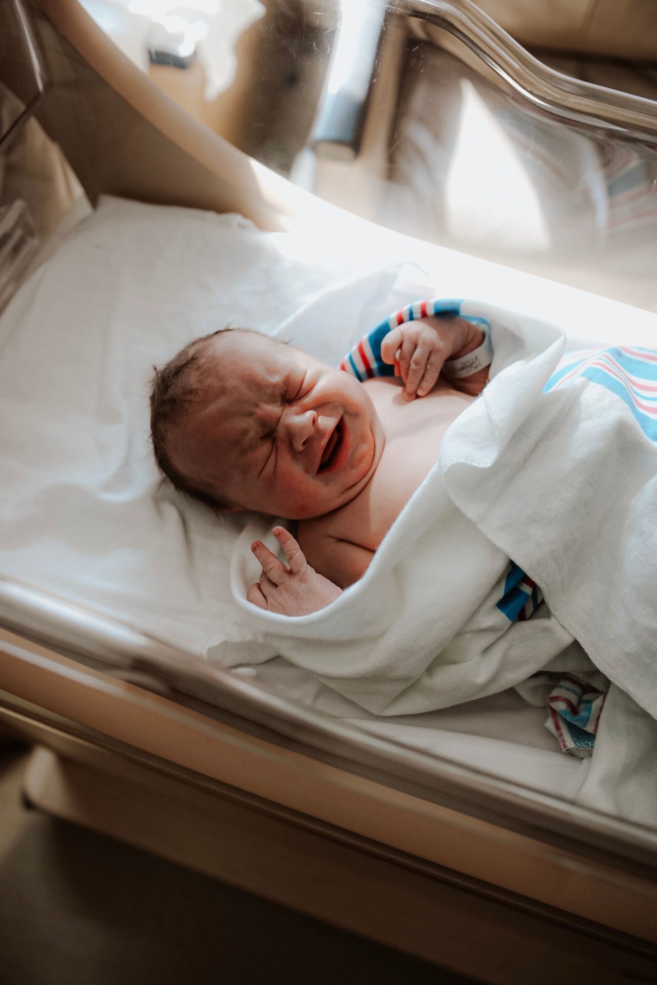 Multiple views of a newborn baby resting on white hospital bedding.
