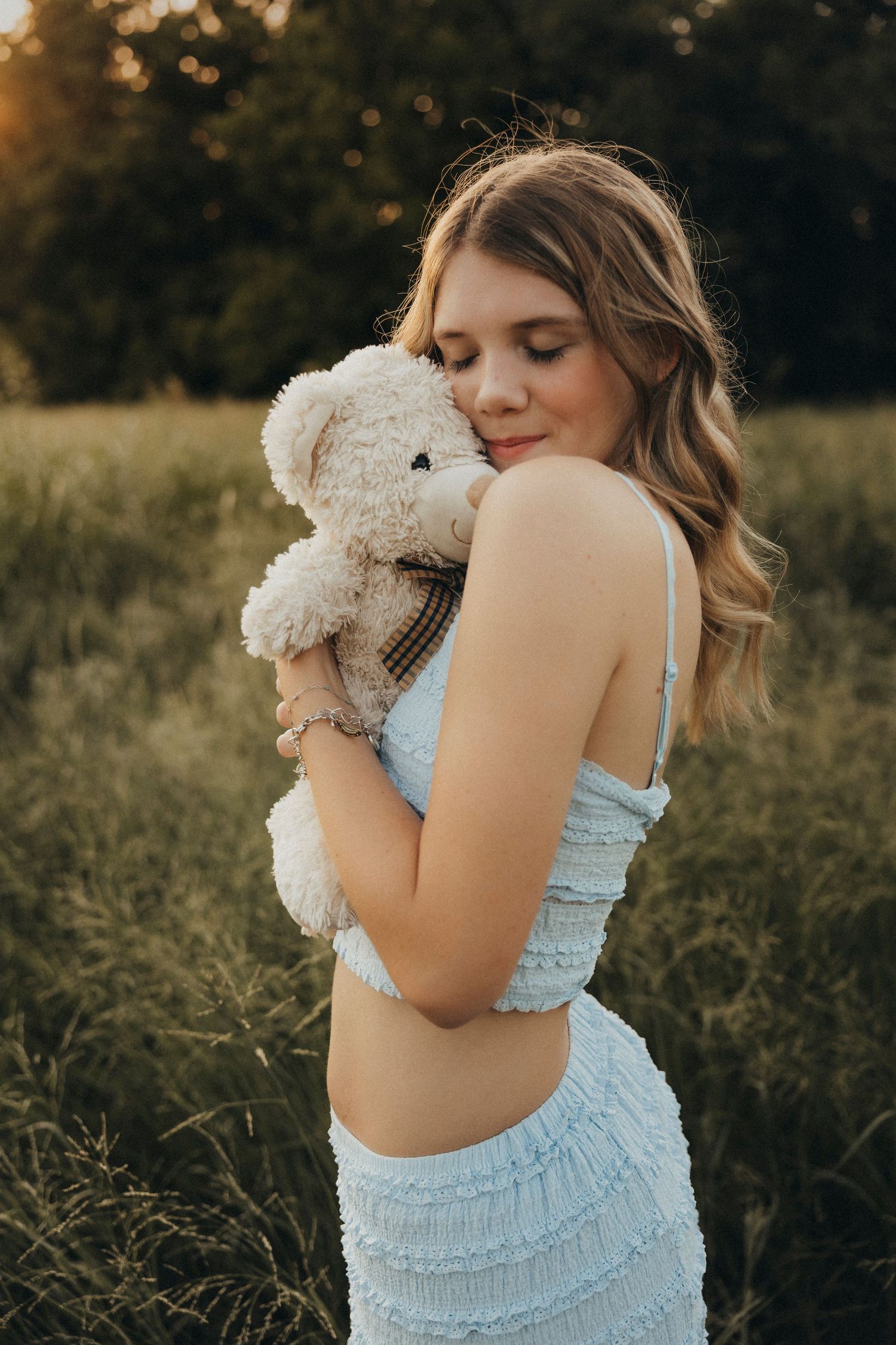 High school senior holding her childhood stuffed animal during a golden hour senior portrait session in Abilene, Texas.