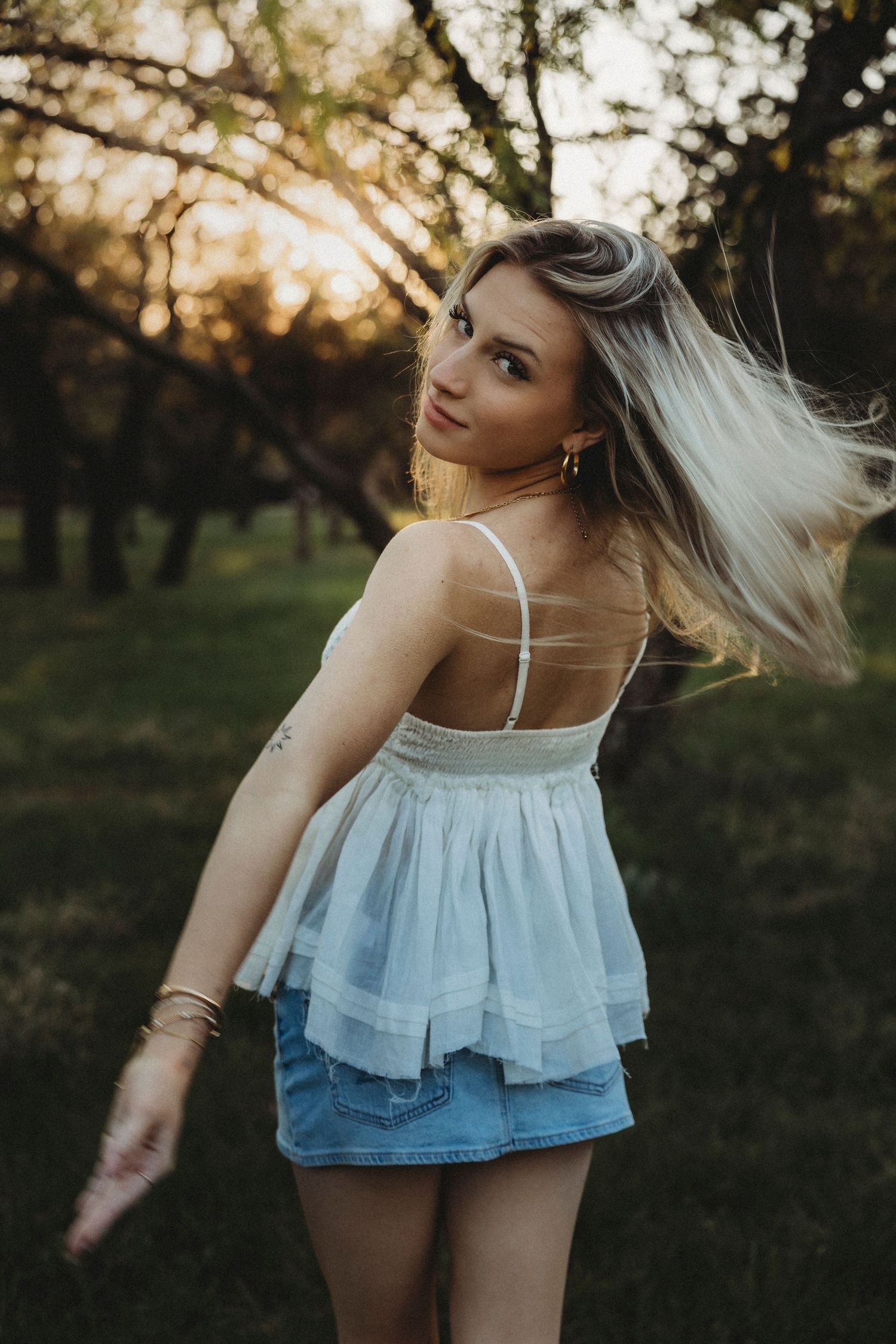 High school senior smiling as her hair catches the golden sunset light during an outdoor senior session in Abilene, Texas