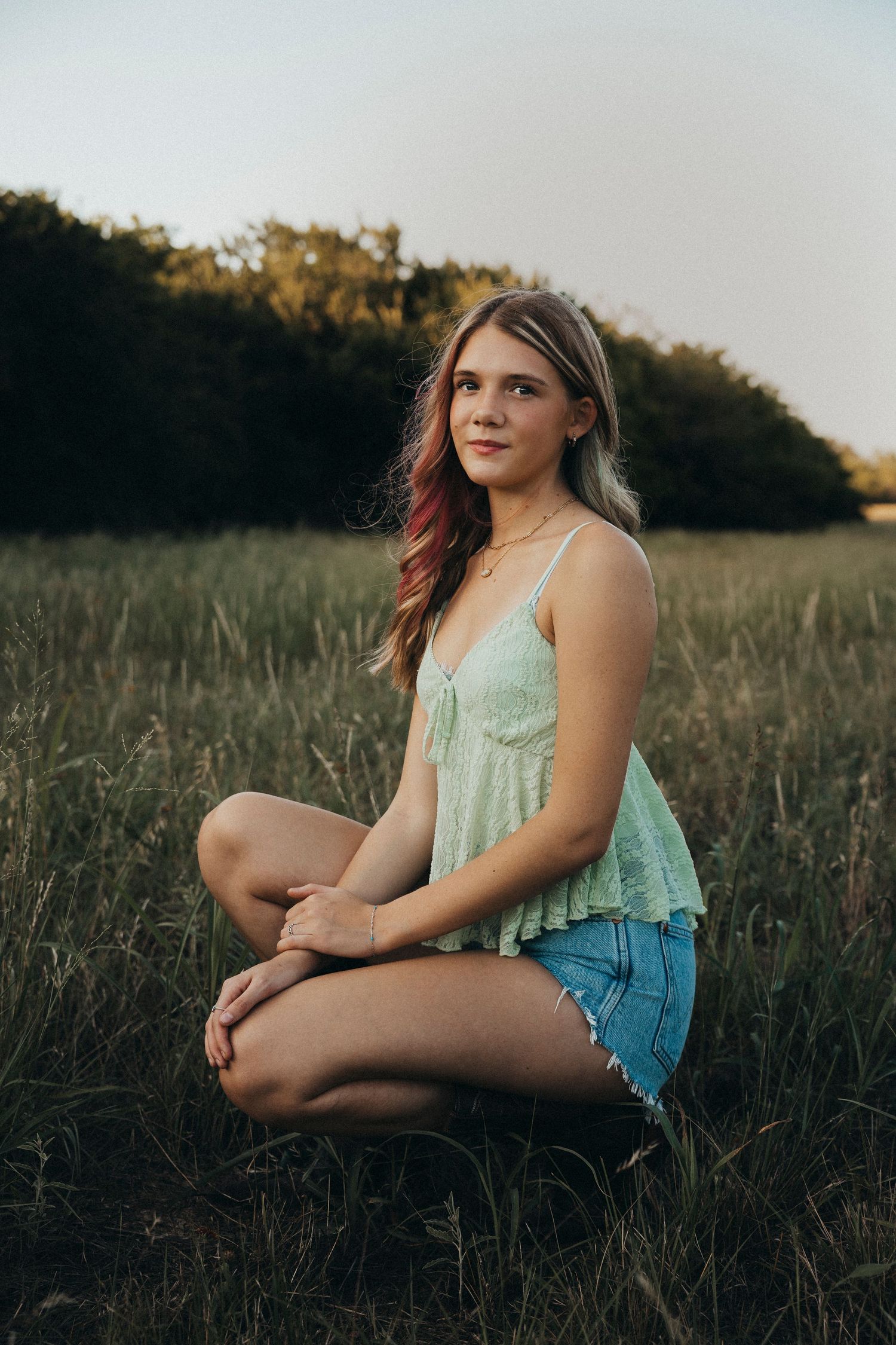Outdoor senior portrait of a high school senior sitting in a grassy field during a sunset senior photography session in Abilene, Texas.