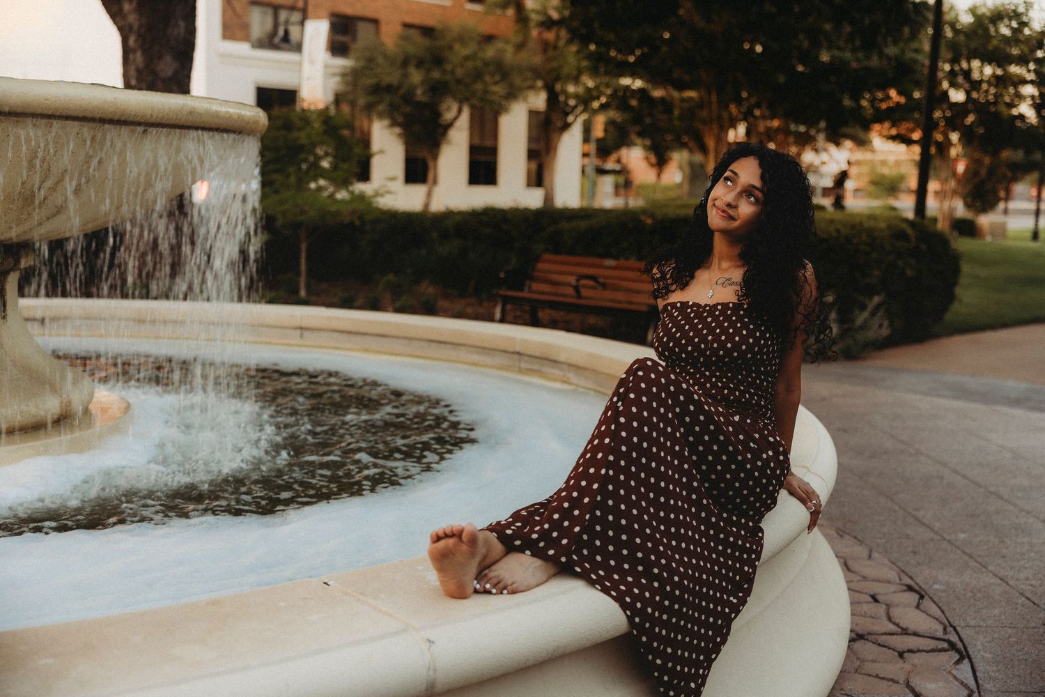 Cooper High School senior sitting on the edge of a fountain in downtown Abilene during a warm golden hour senior session.