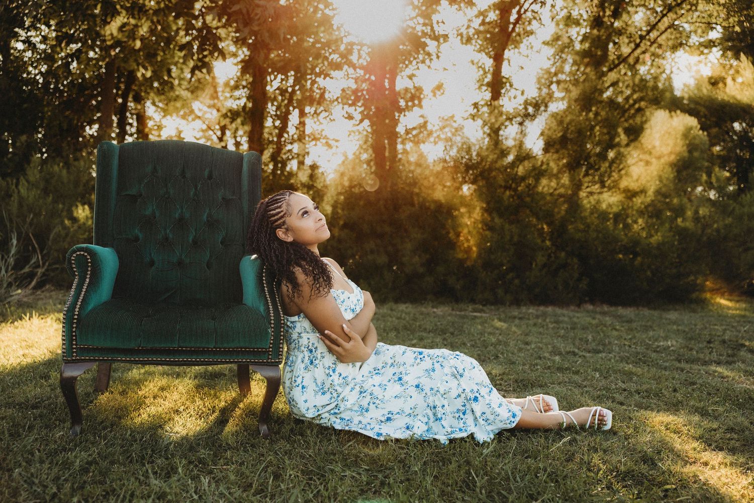 Cooper High School senior relaxing beside a vintage green velvet chair at sunset during a creative outdoor mini session in Abilene, Texas.
