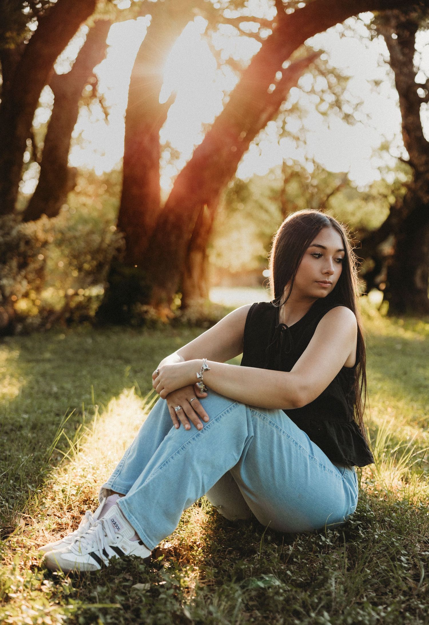 Golden hour senior portrait of a Class of 2027 senior sitting beneath oak trees during an outdoor senior photography session in Abilene, Tex