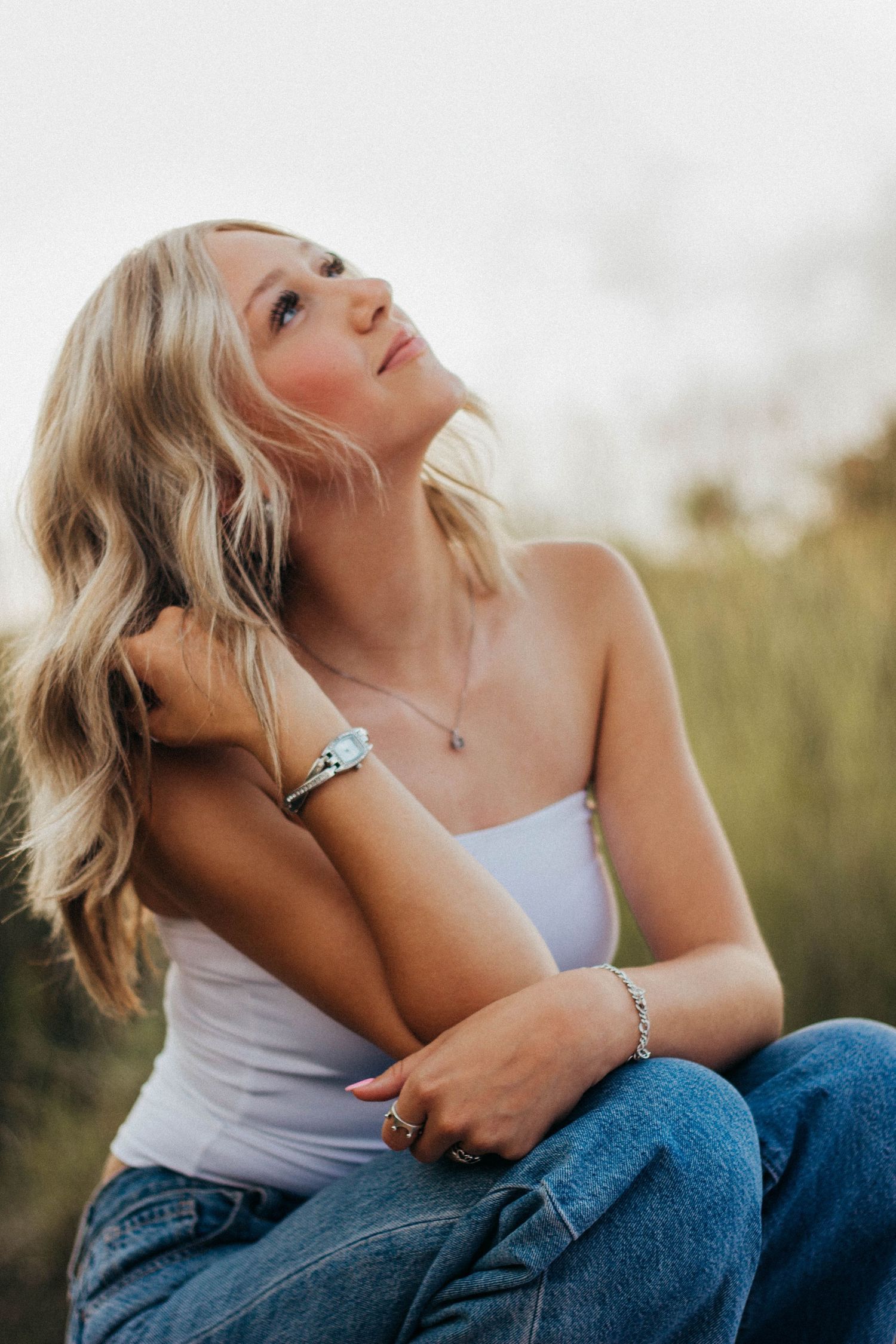 Outdoor senior portrait session in Abilene TX featuring a high school senior seated in tall grass with soft natural light